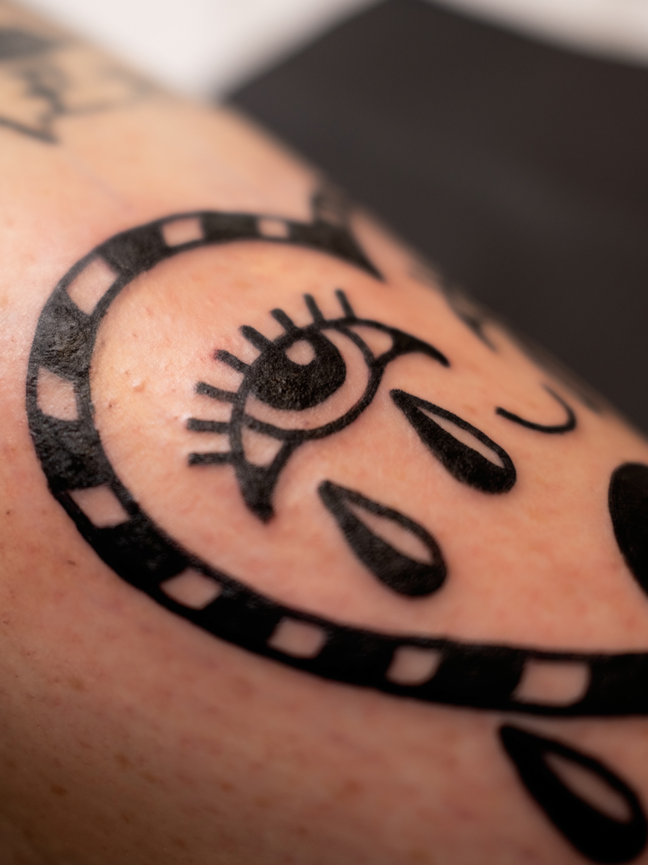 Film strip and eye black and grey tattoo on the forearm by Neto Velasco - Sad Cat Tattoo, Austin, Texas