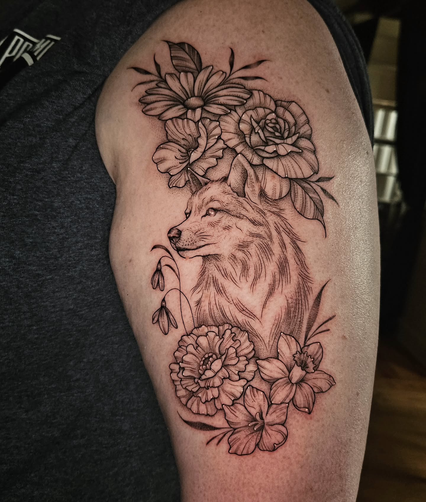 Wolf and flowers realism tattoo on the upper arm by Courtlyn Bliss