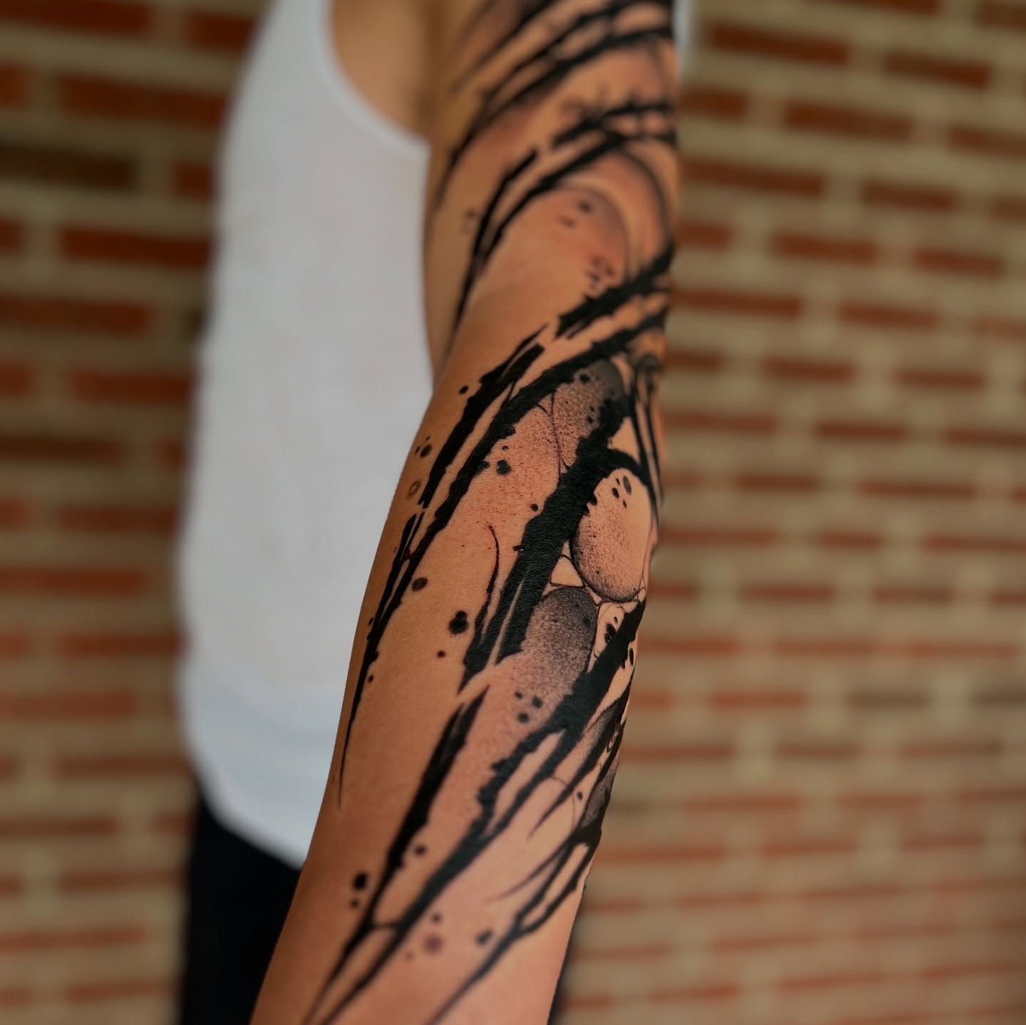Abstract splatter black and grey tattoo on the forearm by Cameron Jenkins