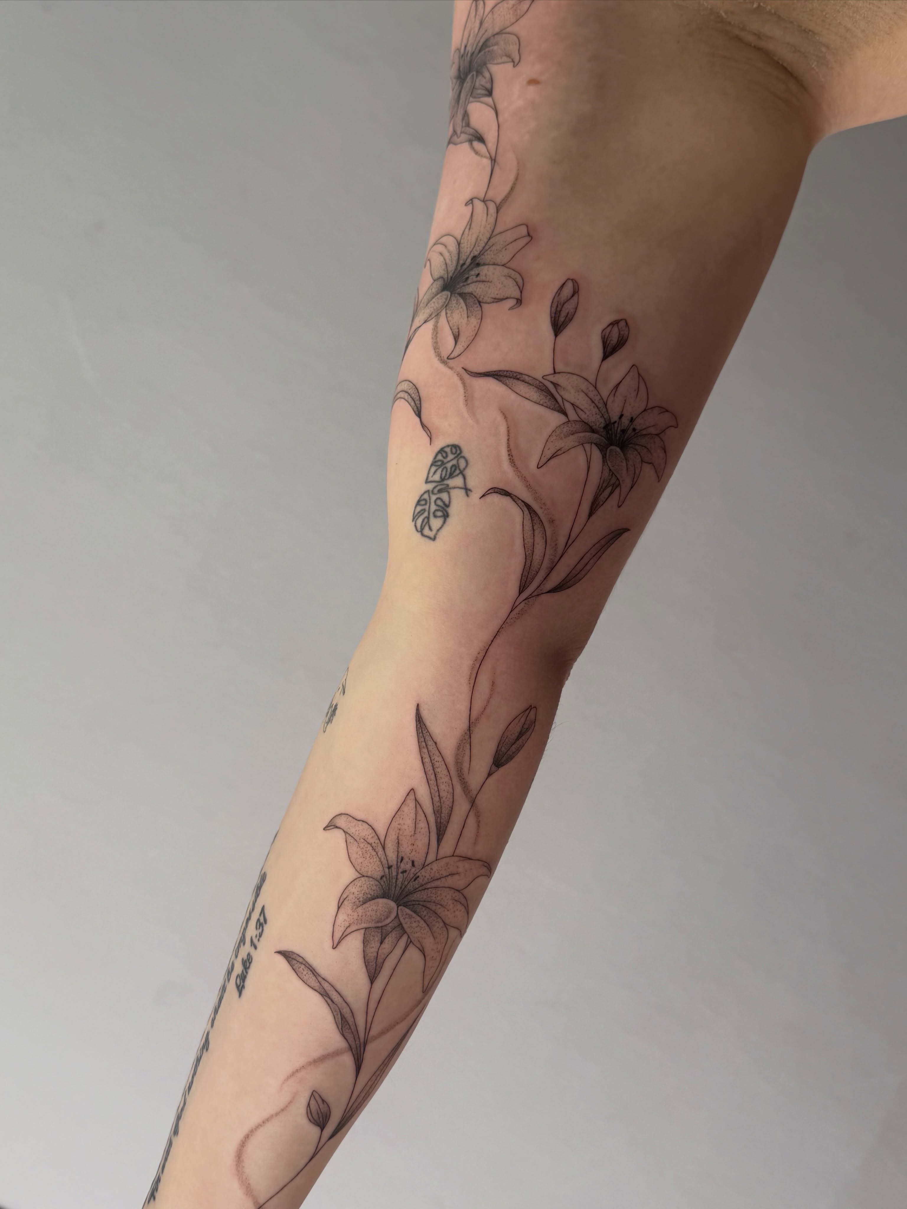 Lilies black and grey tattoo on the forearm by Henesee Parfitt