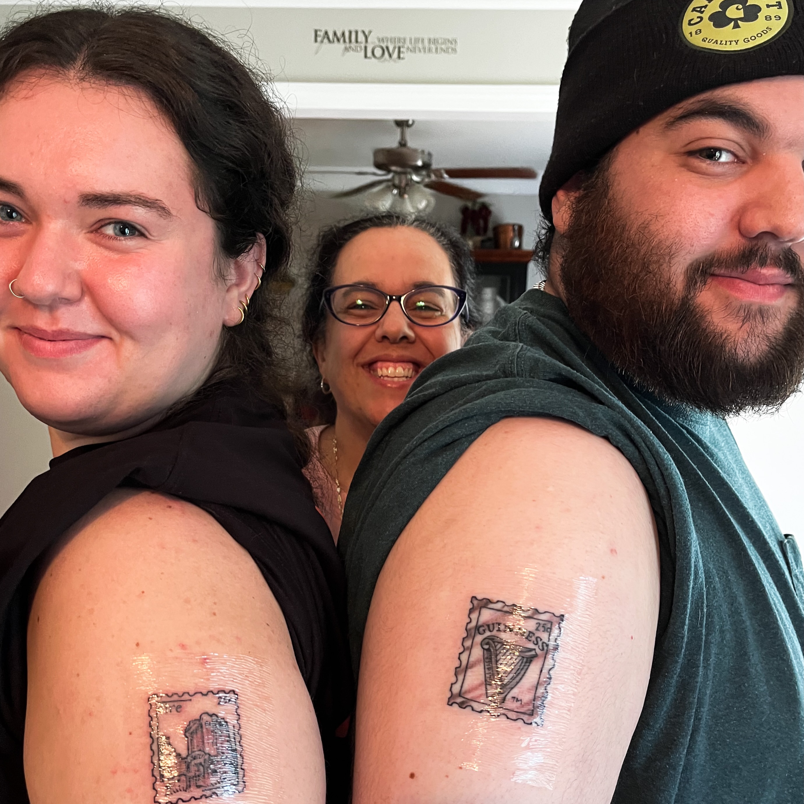 Guinness stamp black and grey tattoo on the upper arm by Janelle Cuba