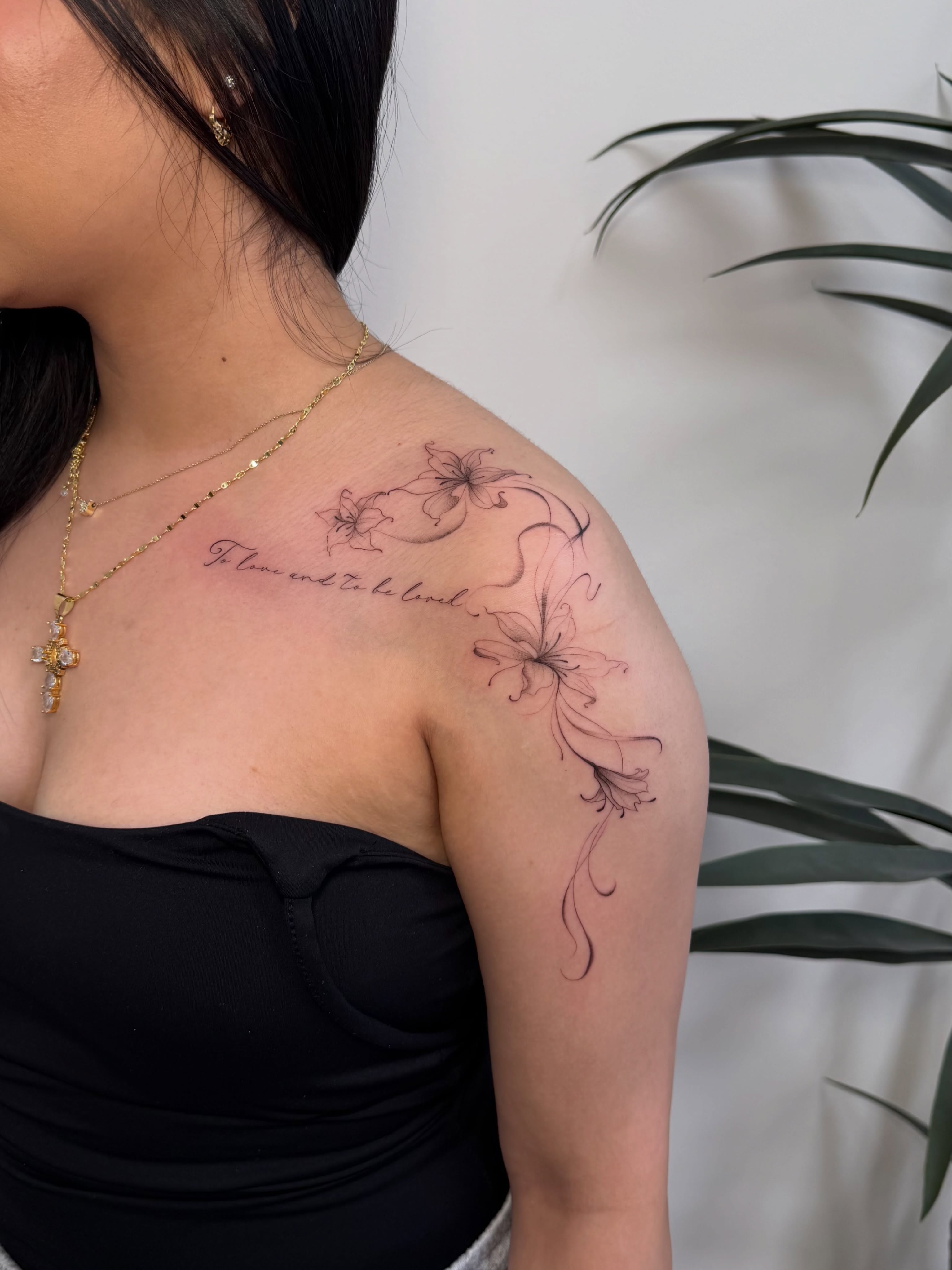 Flowers and script black and grey tattoo on the shoulder by David