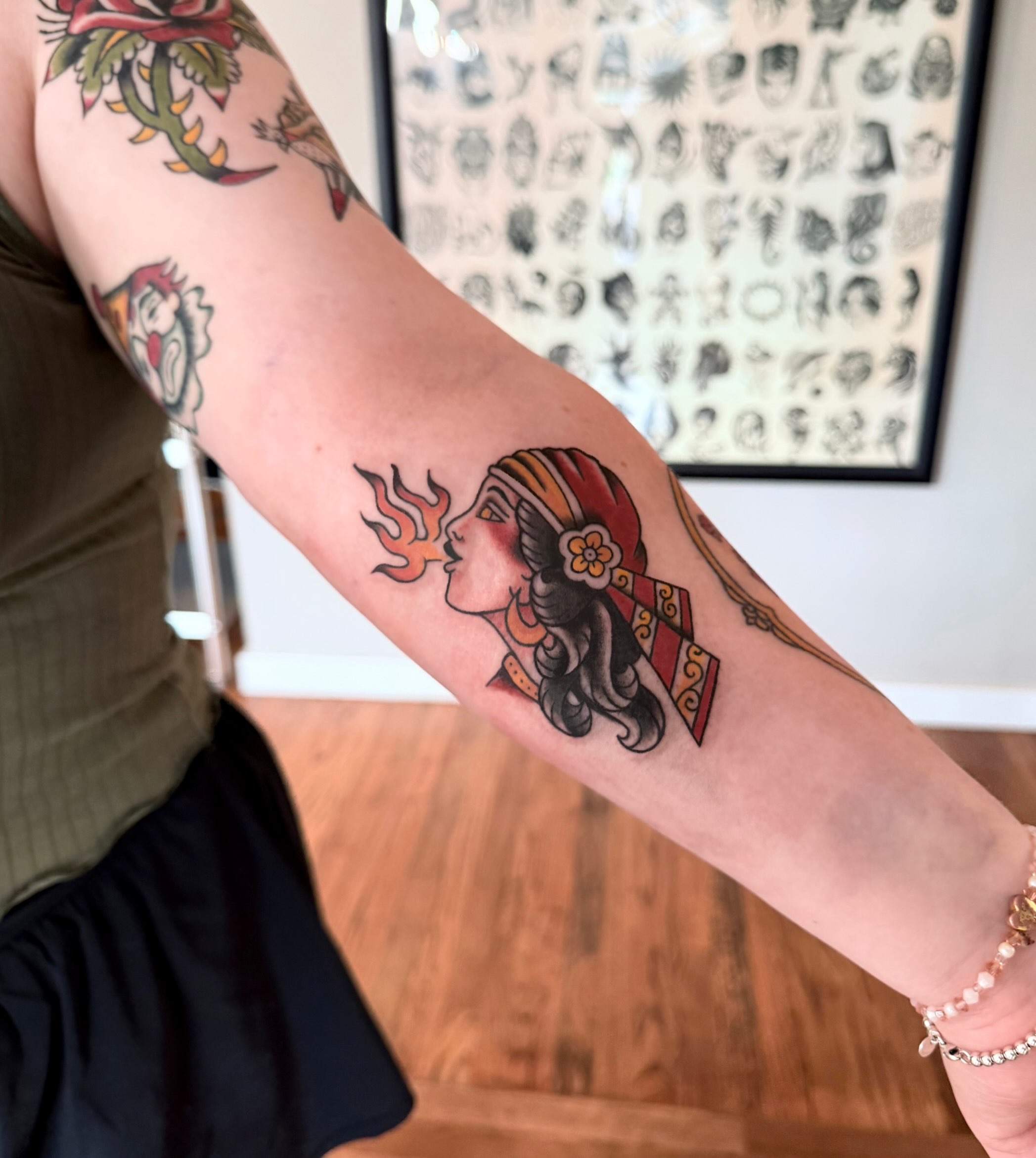 Woman blowing fire American traditional tattoo on the forearm by M
