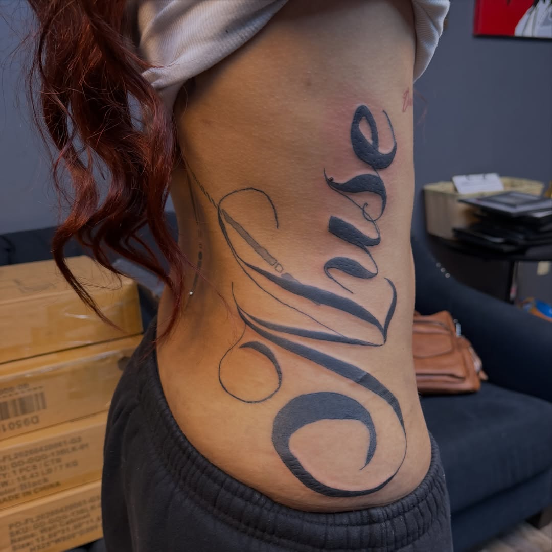 Oluse lettering script tattoo on the ribs by XoXandrea.Ink, Kansas City, Missouri