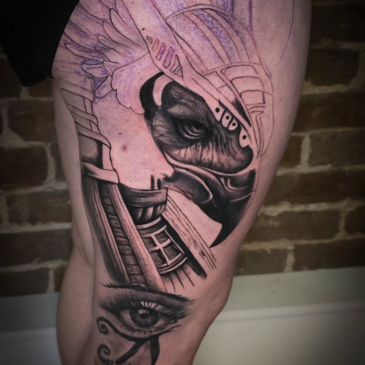 Helmeted figure with eye realism tattoo on the thigh by John Christo Blake