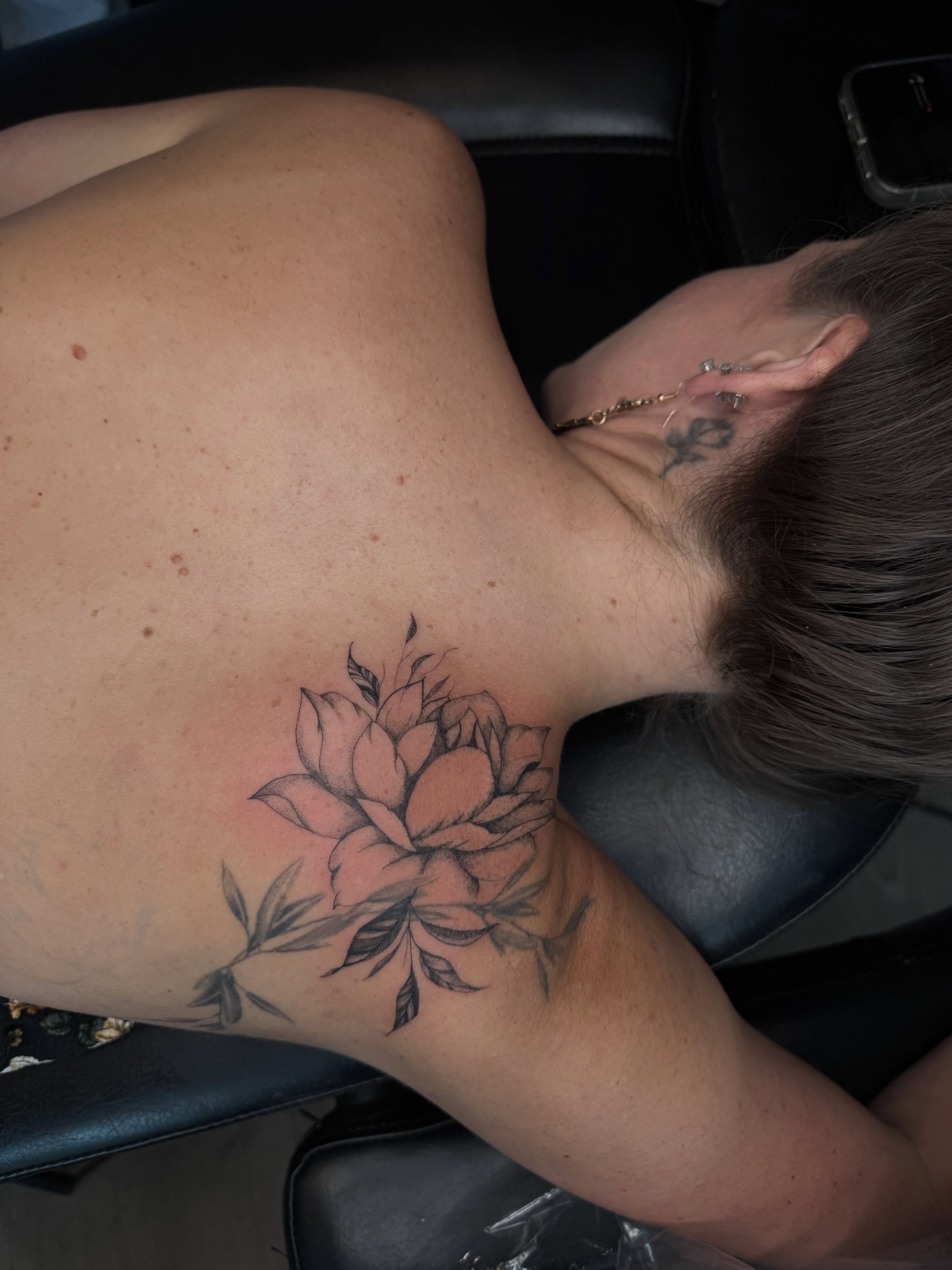 Flower black and grey tattoo on the back by Ryleigh Benjamin