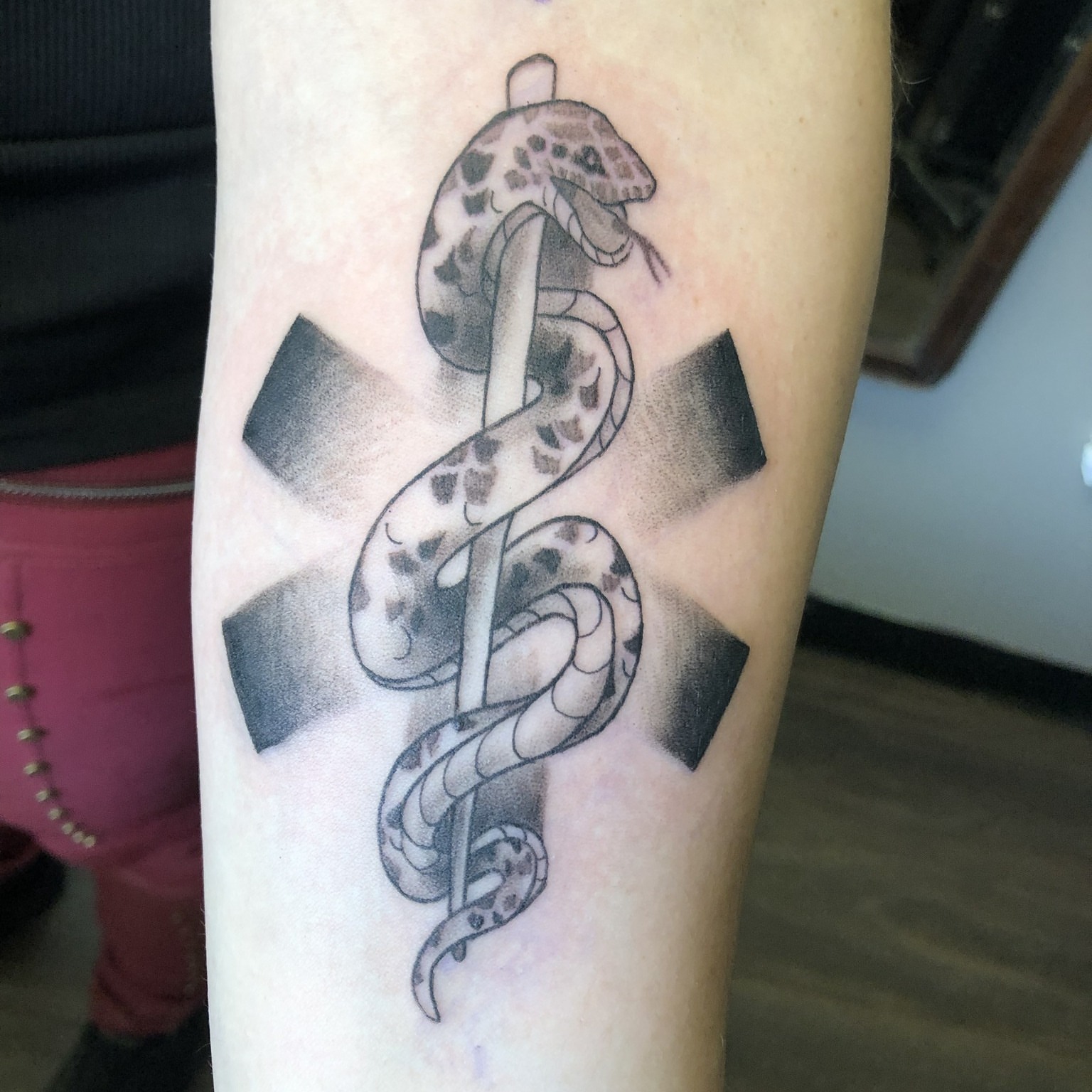 Snake and cross black and grey tattoo on the forearm by Rowan Lee