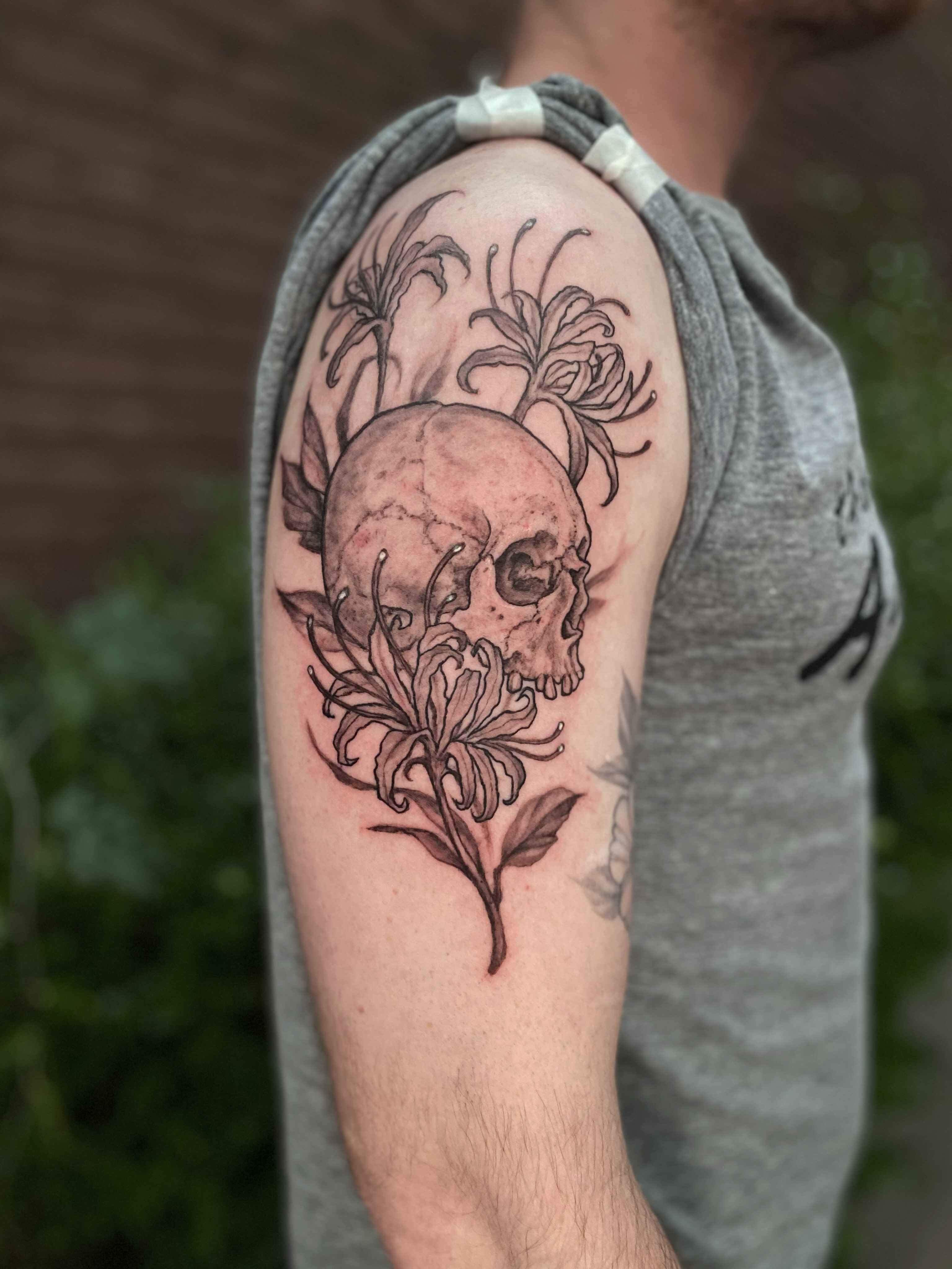 Skull and flowers realism tattoo on the forearm by Dana Jones