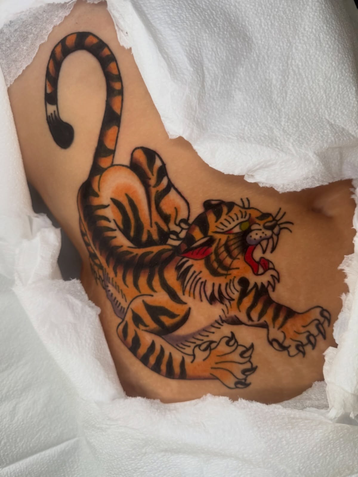 Tiger American traditional tattoo on the thigh by Lexie Graff