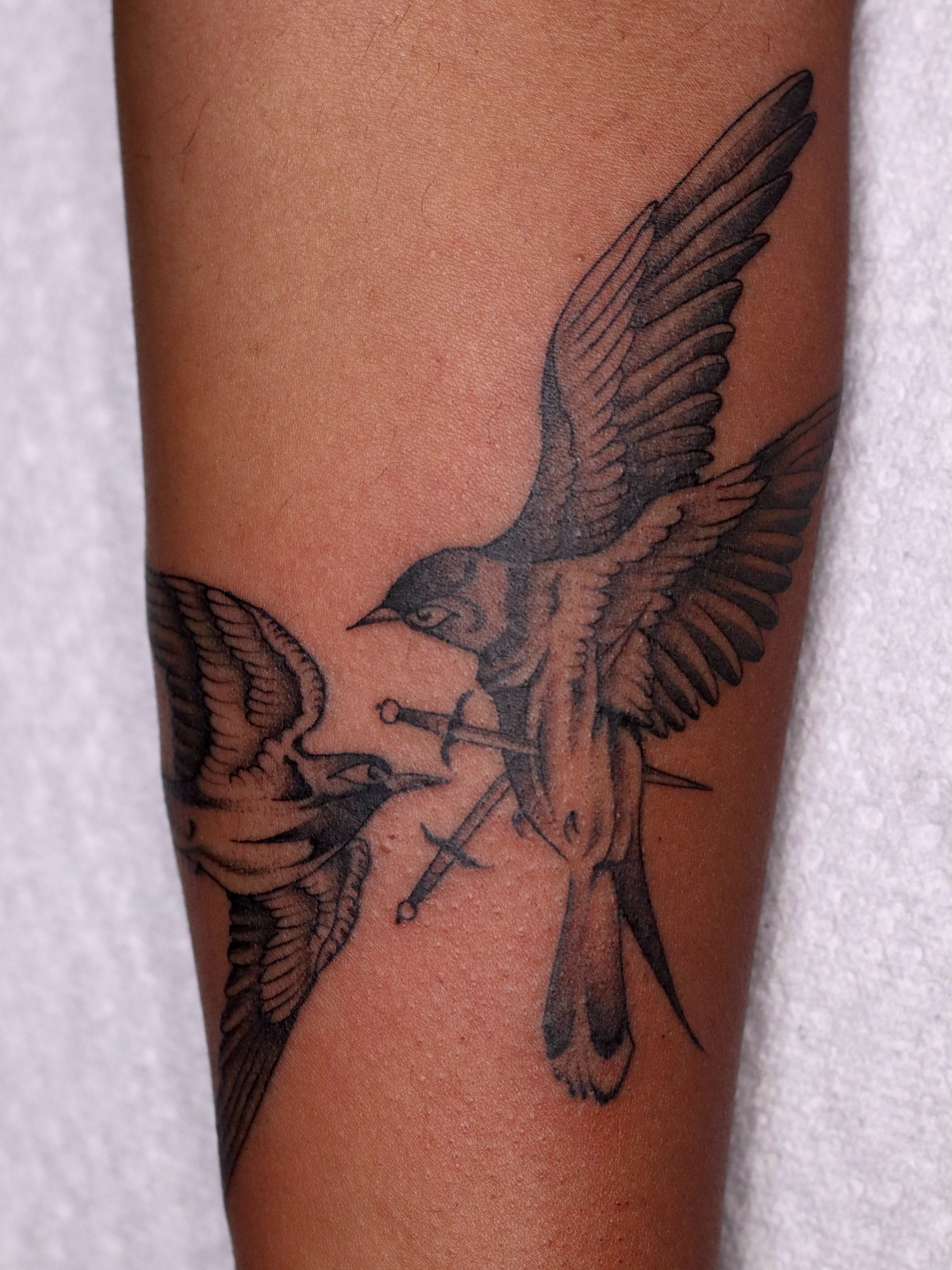 Birds and swords black and grey tattoo on the forearm by Nik Checots