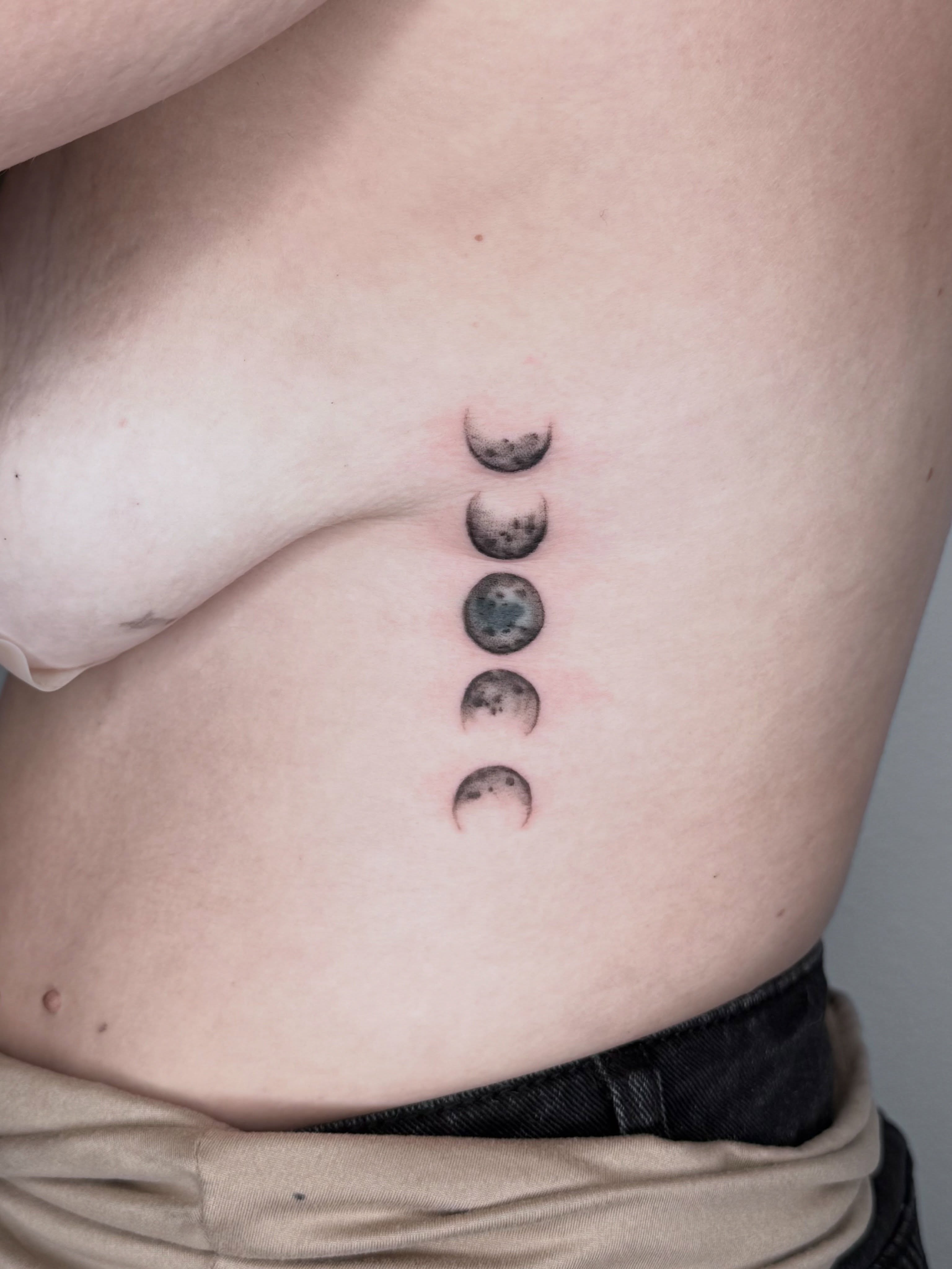 Phases of the moon dotwork tattoo on the ribs by Ashley Limon