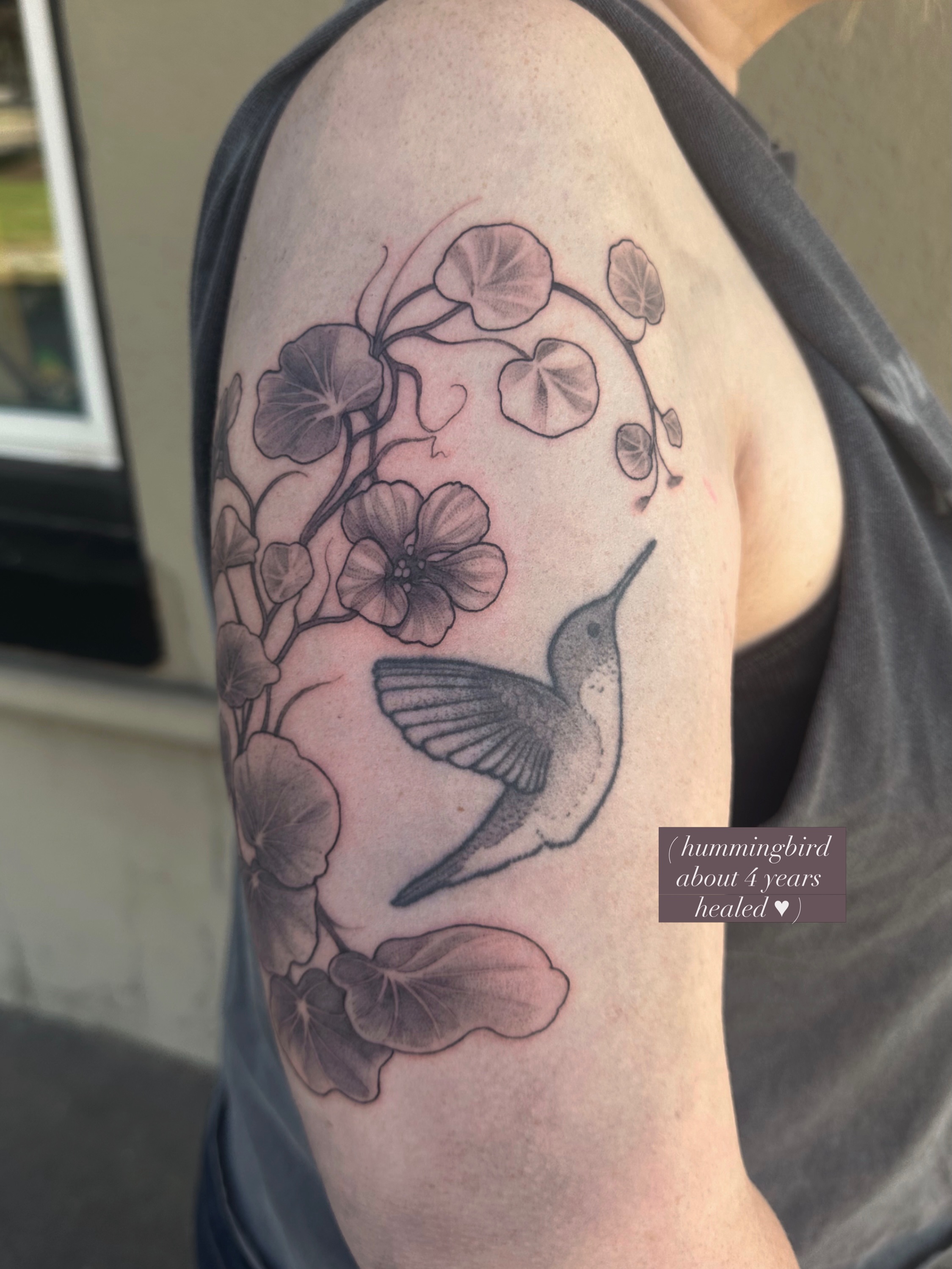 Hummingbird black and grey tattoo on the upper arm by Emma Thompson