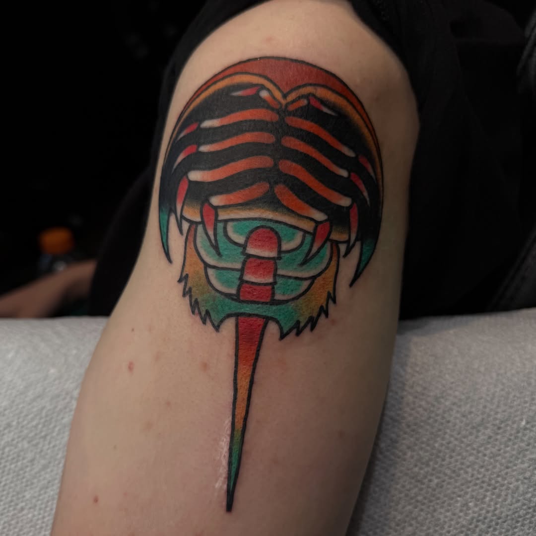 Mask geometric tattoo on the upper arm by Mercy Dean