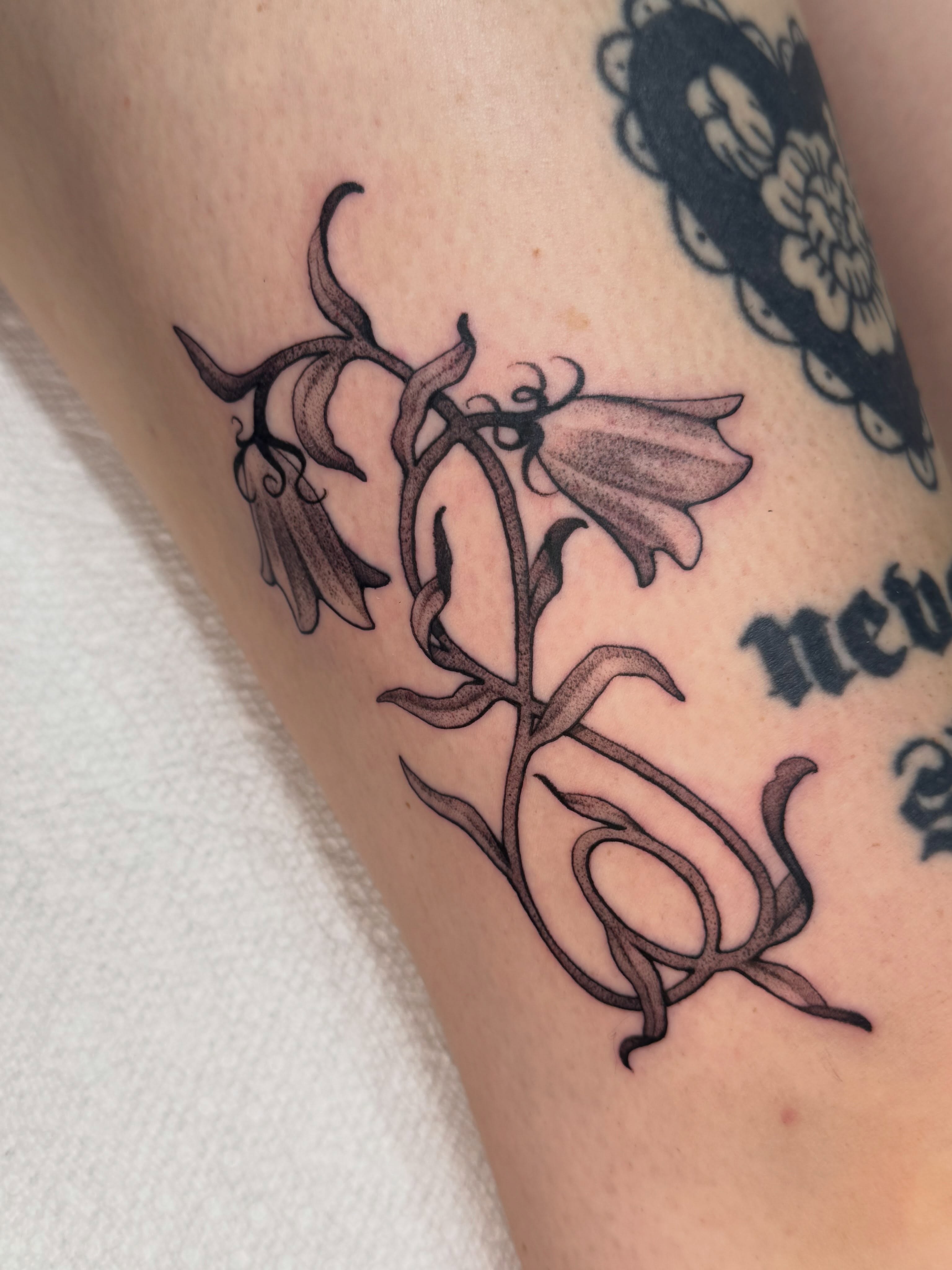 Bell flowers black and grey tattoo on the forearm by Marina Spell