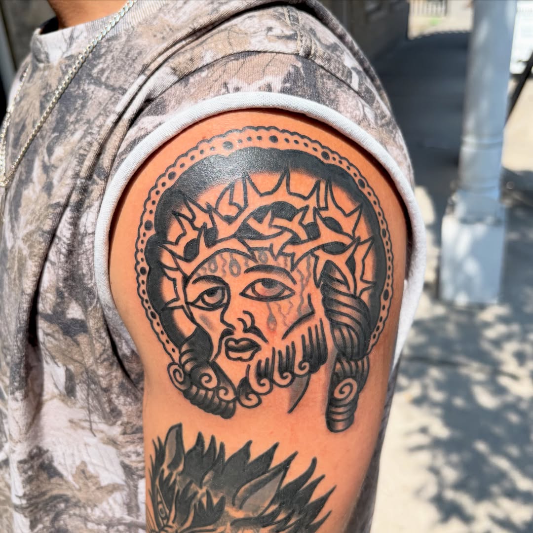 Sun and face black and grey tattoo on the upper arm by Braedon 🎱