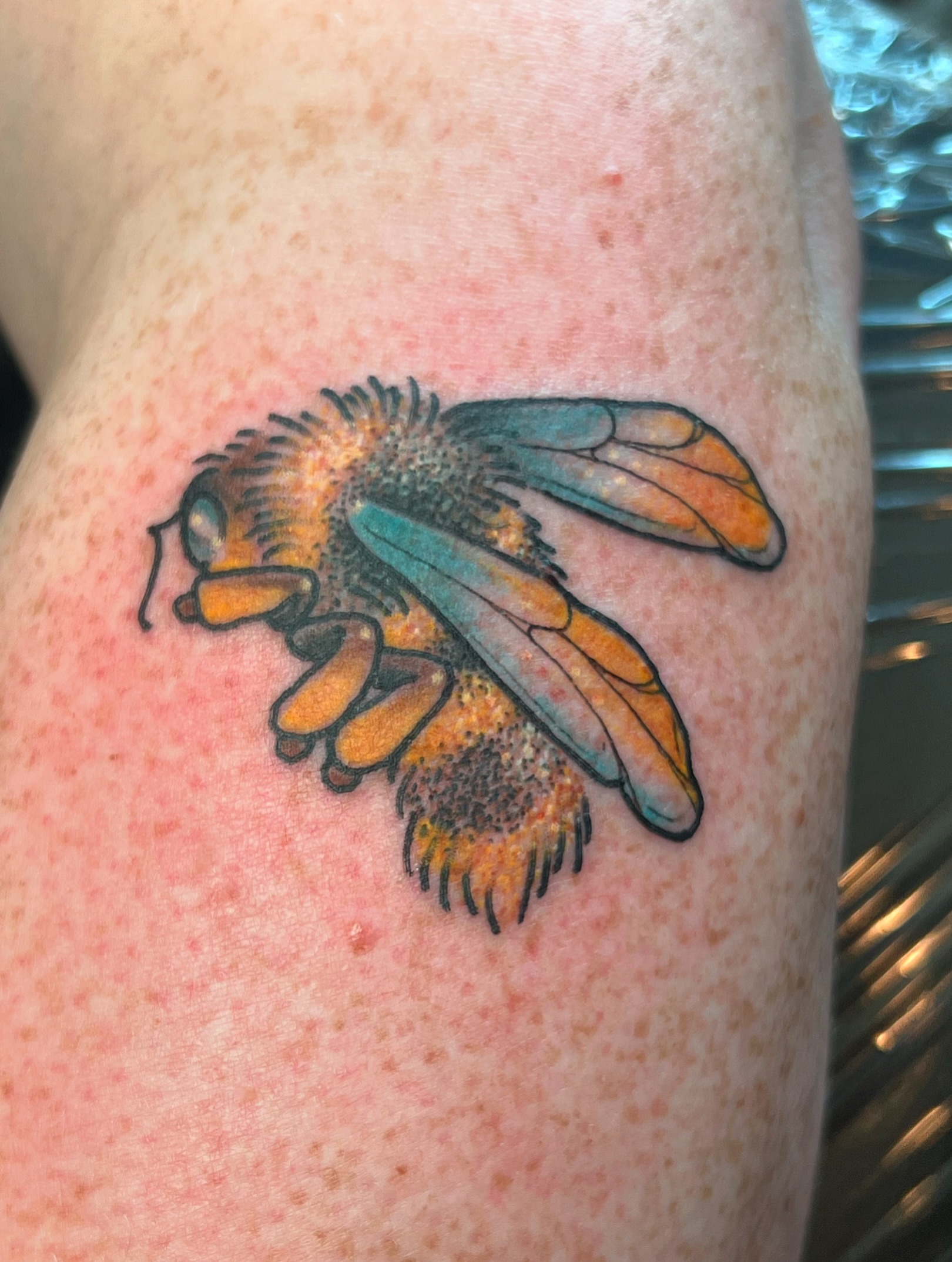Bee new school tattoo on the upper arm by Andrea Patterson