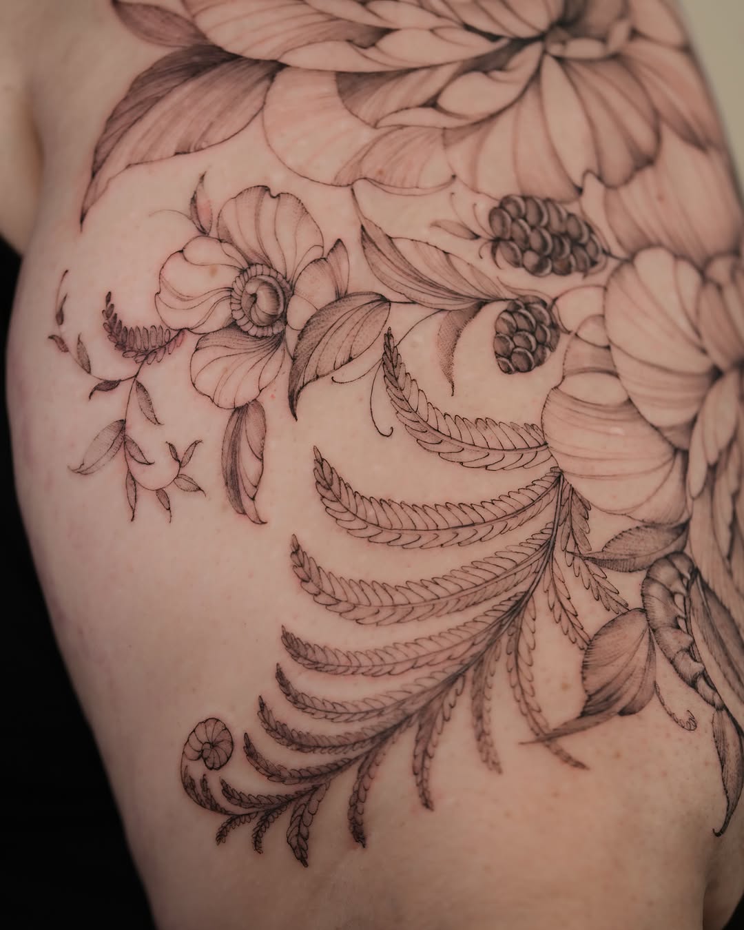 Floral arrangement black and grey tattoo on the shoulder by Zalina Loriia