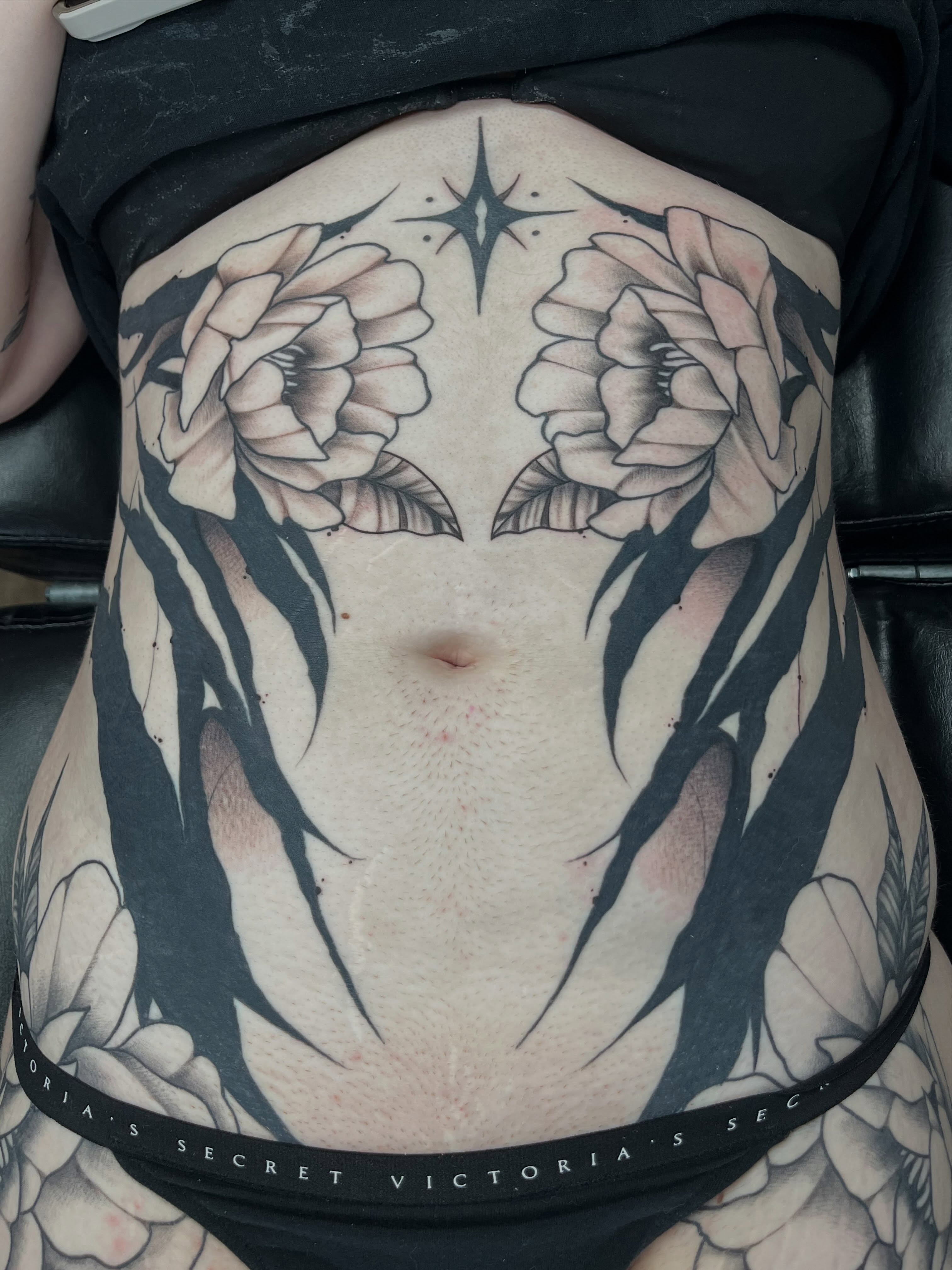 Floral black and grey tattoo on the torso by Ty’s Tattoos