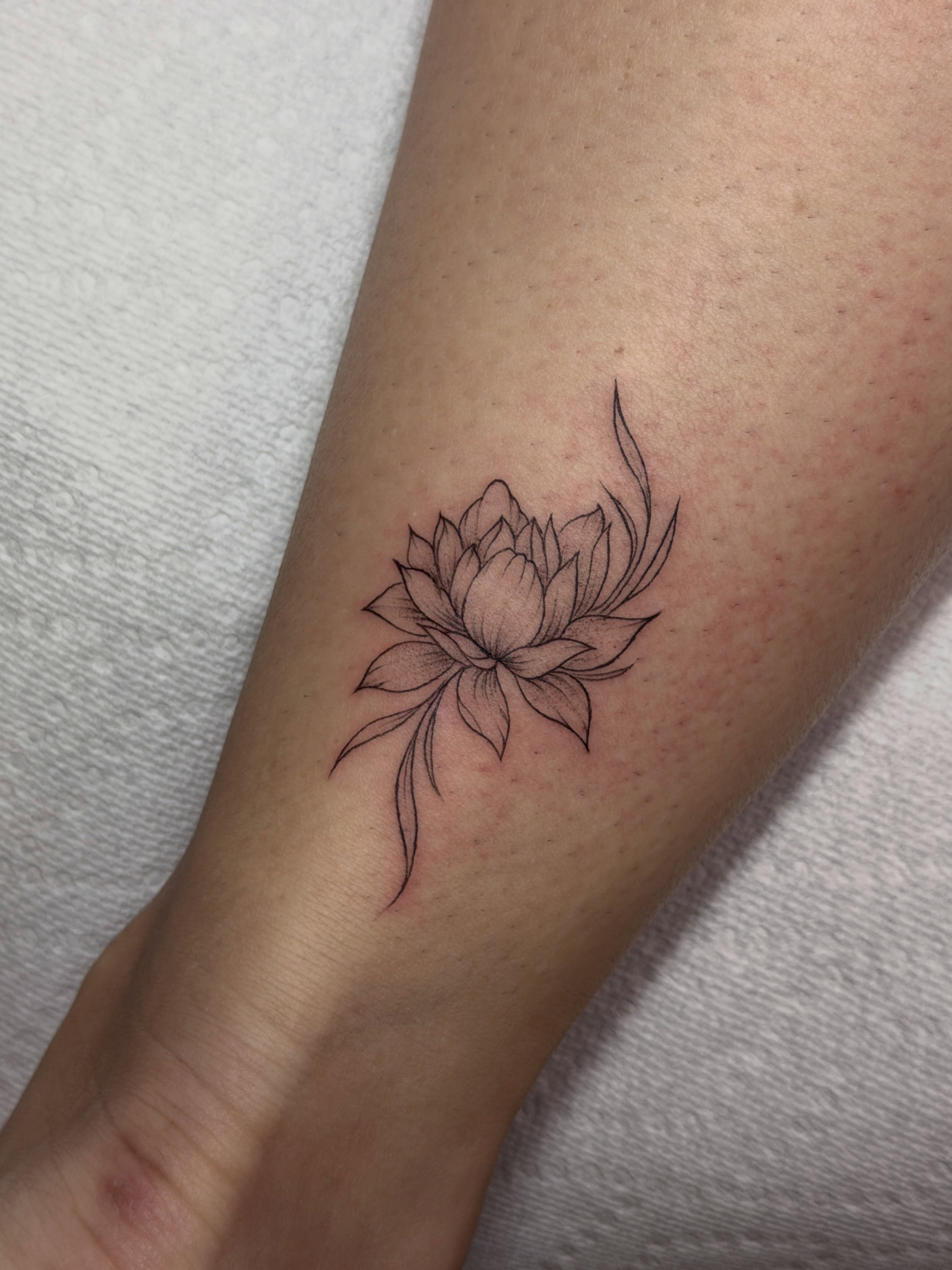 Lotus flower black and grey tattoo on the forearm by Baka Ink