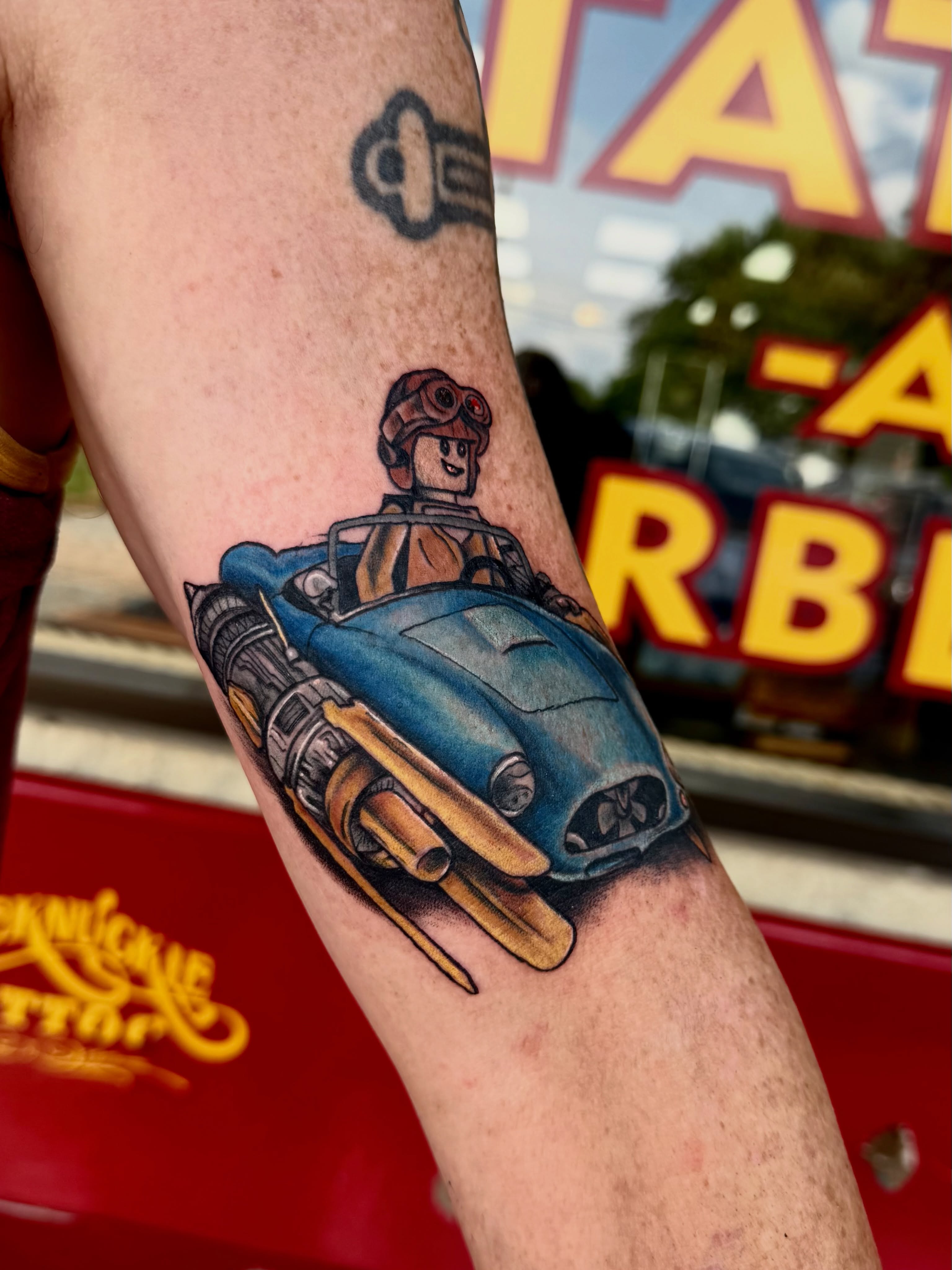 Steampunk car and pilot American traditional tattoo on the forearm by Josh Kronauer