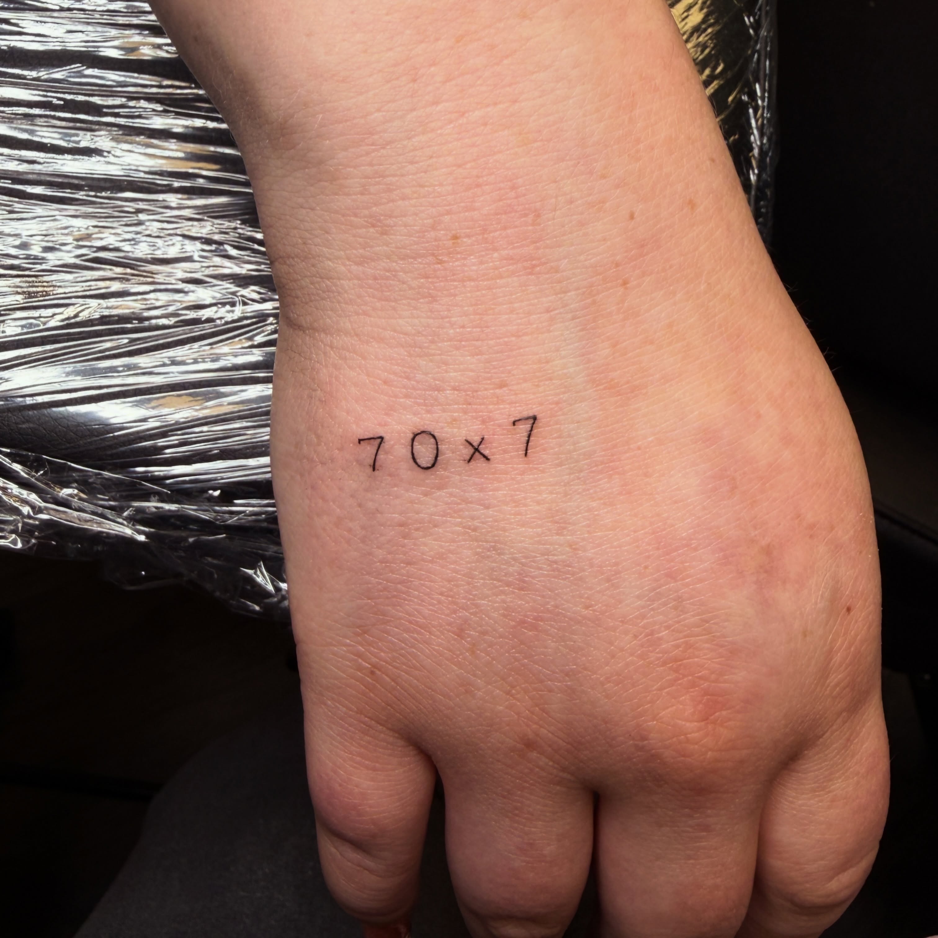 70x7 lettering script tattoo on the hand by Pretty Ugly Tattoos