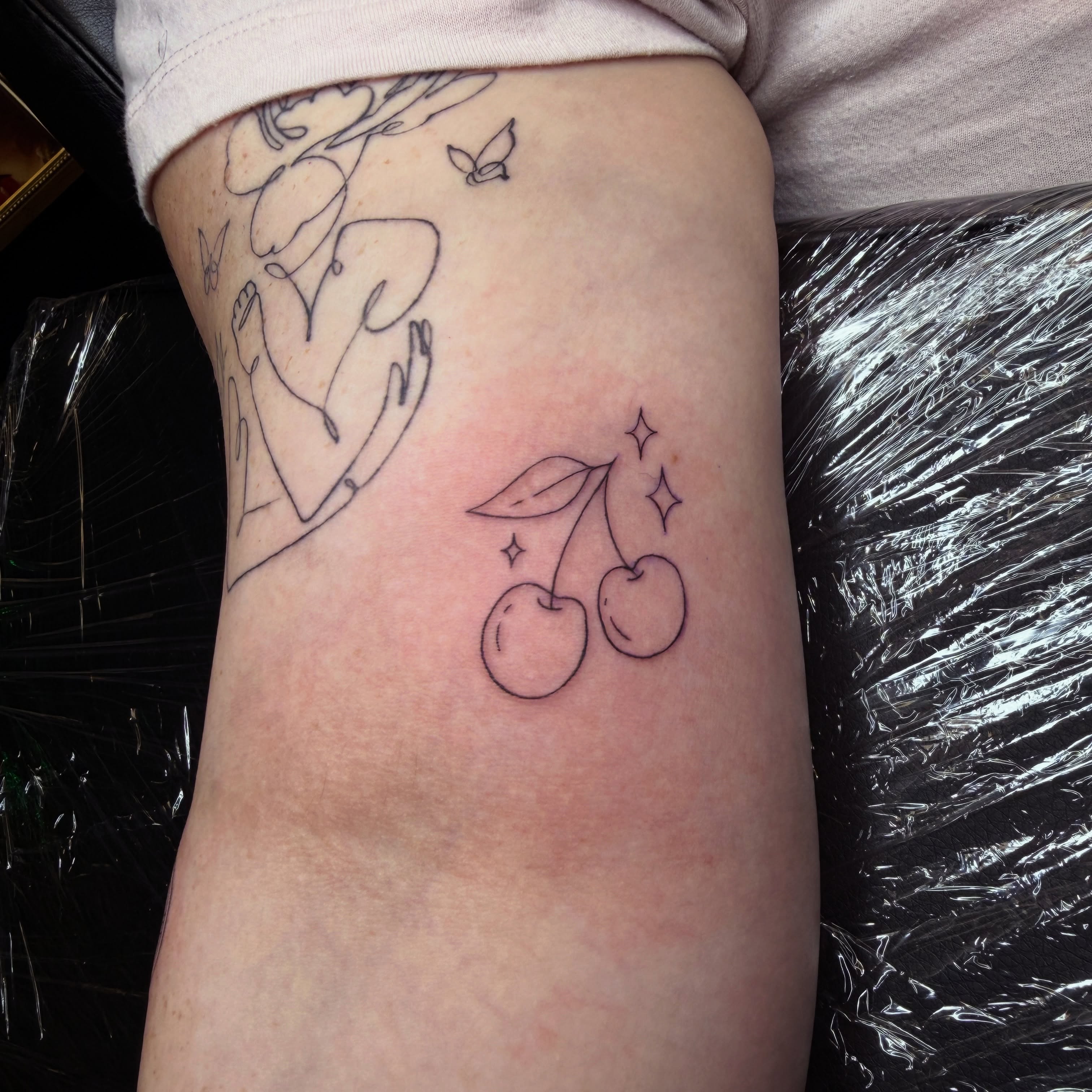Cherries minimalist tattoo on the thigh by Pretty Ugly Tattoos