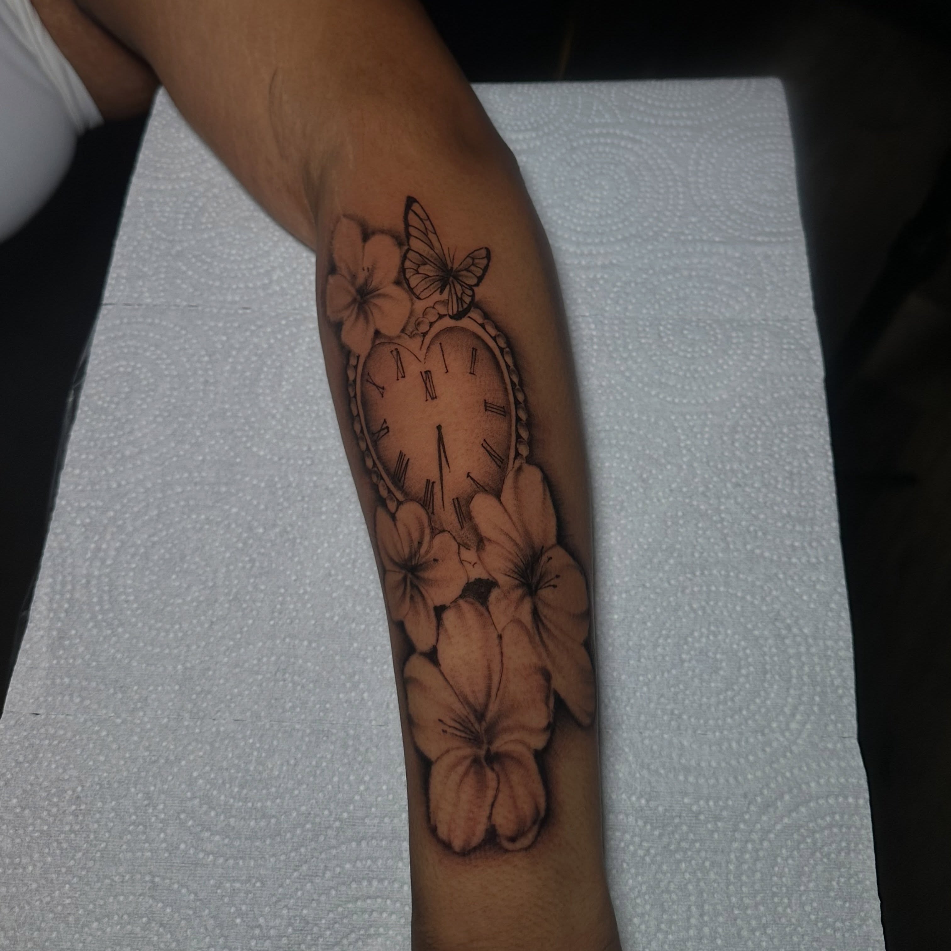 Clock and flowers black and grey tattoo on the forearm by @tattedbytuck