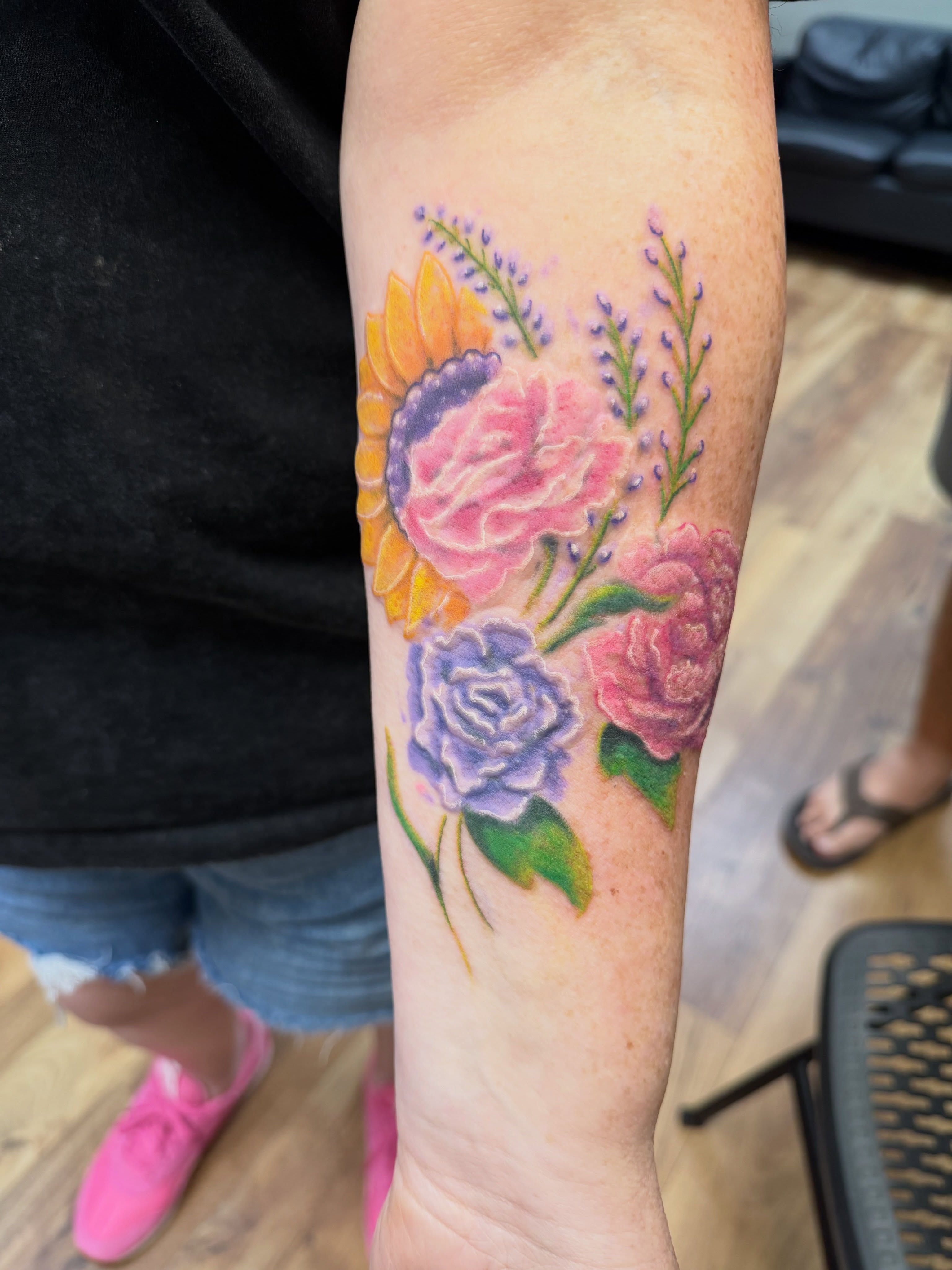 Floral bouquet watercolor tattoo on the forearm by Loki Shane DeFriece