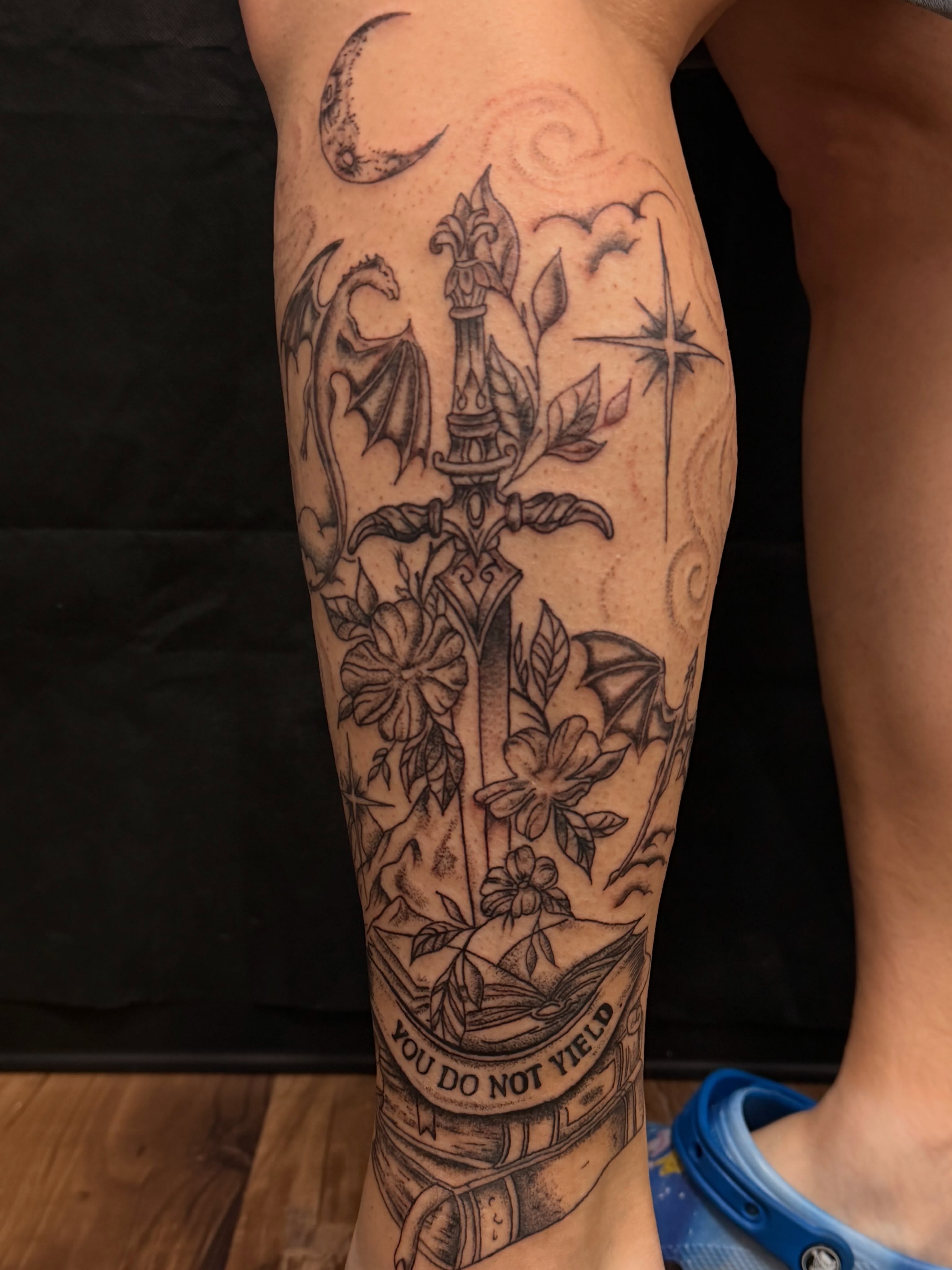 Sword and flowers realism tattoo on the calf by cortez