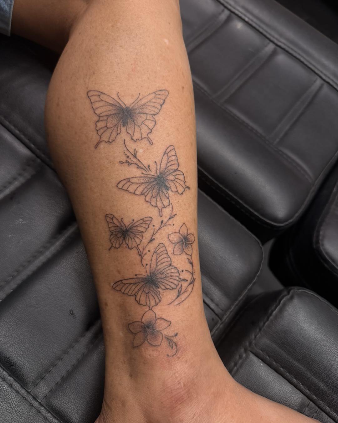 Butterflies and flowers black and grey tattoo on the forearm by Flamboyant