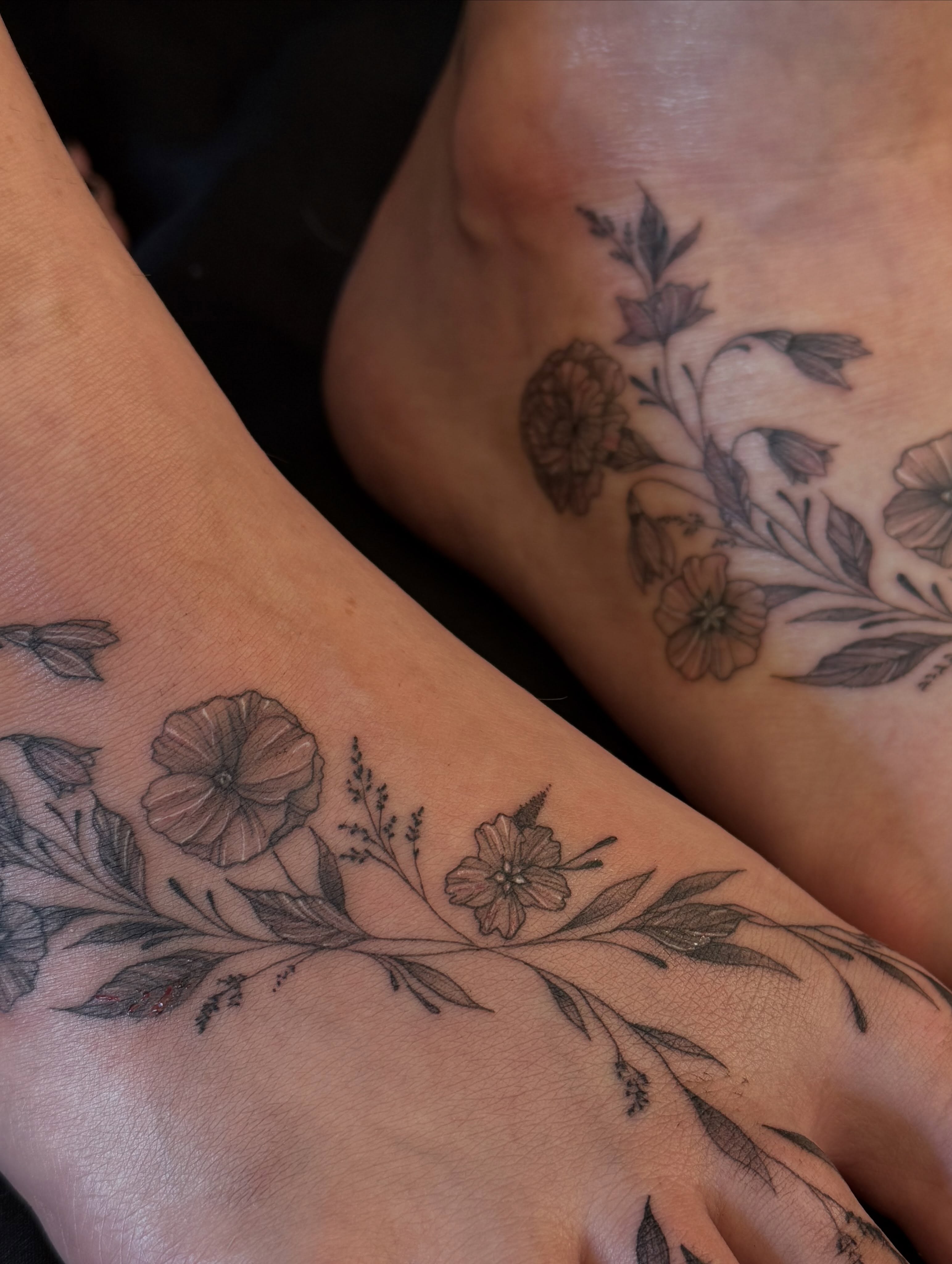 Floral arrangement black and grey tattoo on the foot by Dre