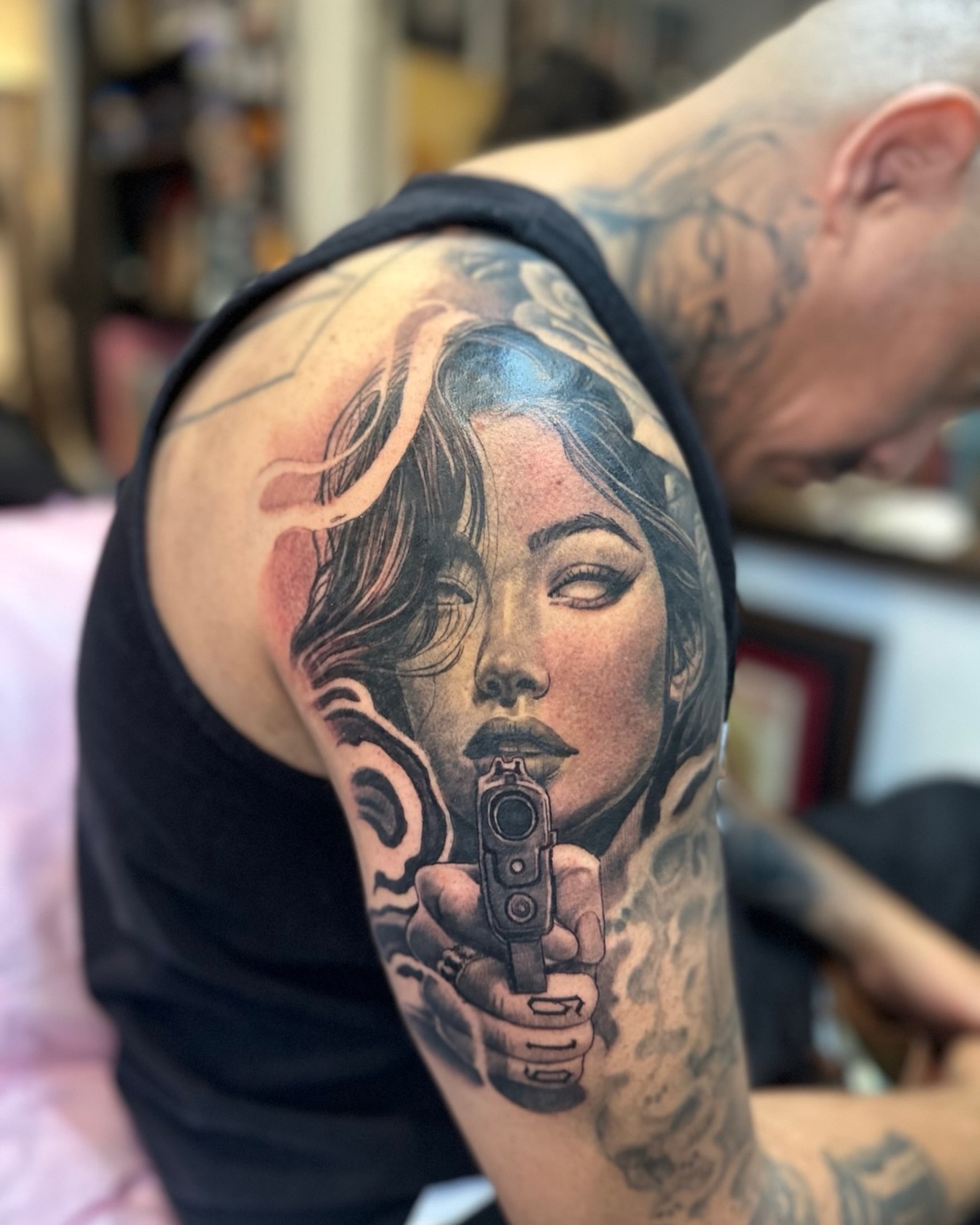 Woman with gun realism tattoo on the upper arm by Tattoos By Deft