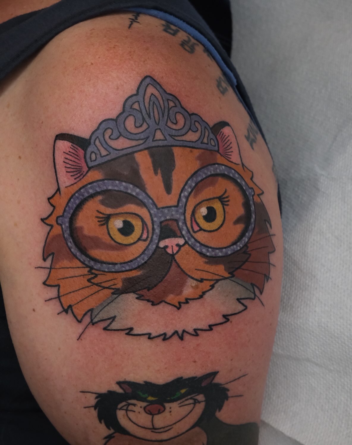 Cat wearing glasses and tiara realism tattoo on the shoulder by James Maxwell