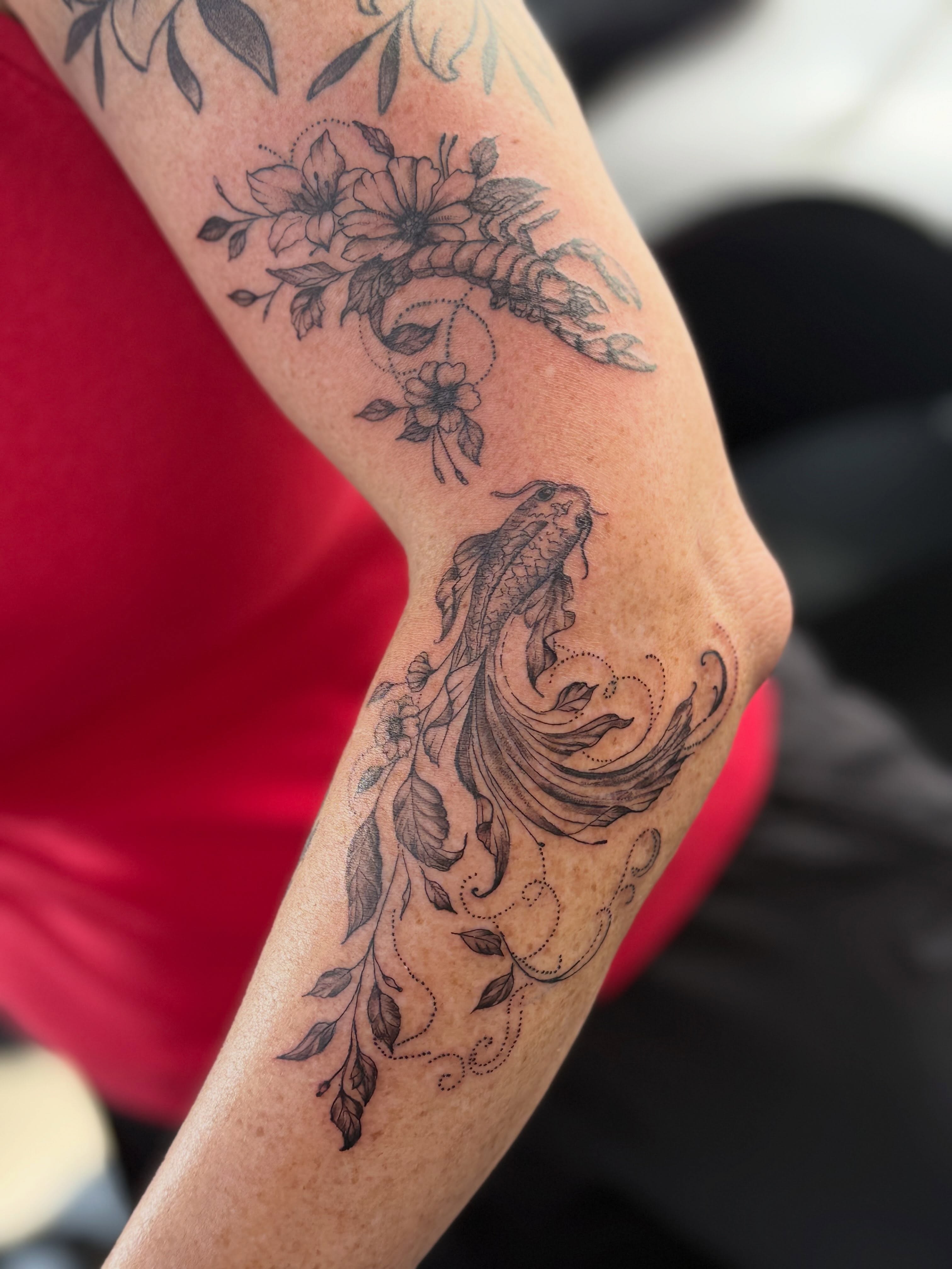 Koi fish and floral black and grey tattoo on the forearm by Tetiana