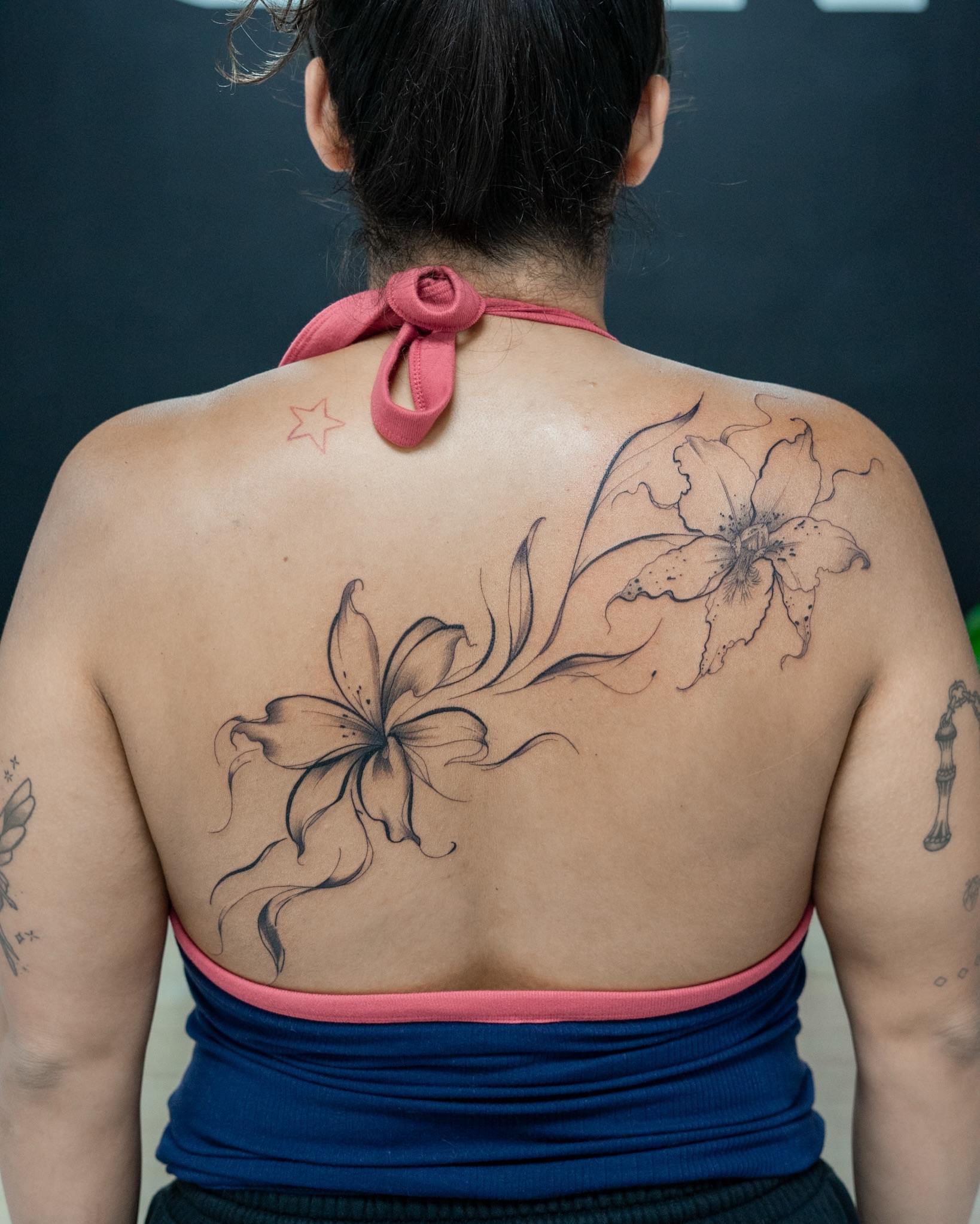 Lilies black and grey tattoo on the back by The Tattoo Plug