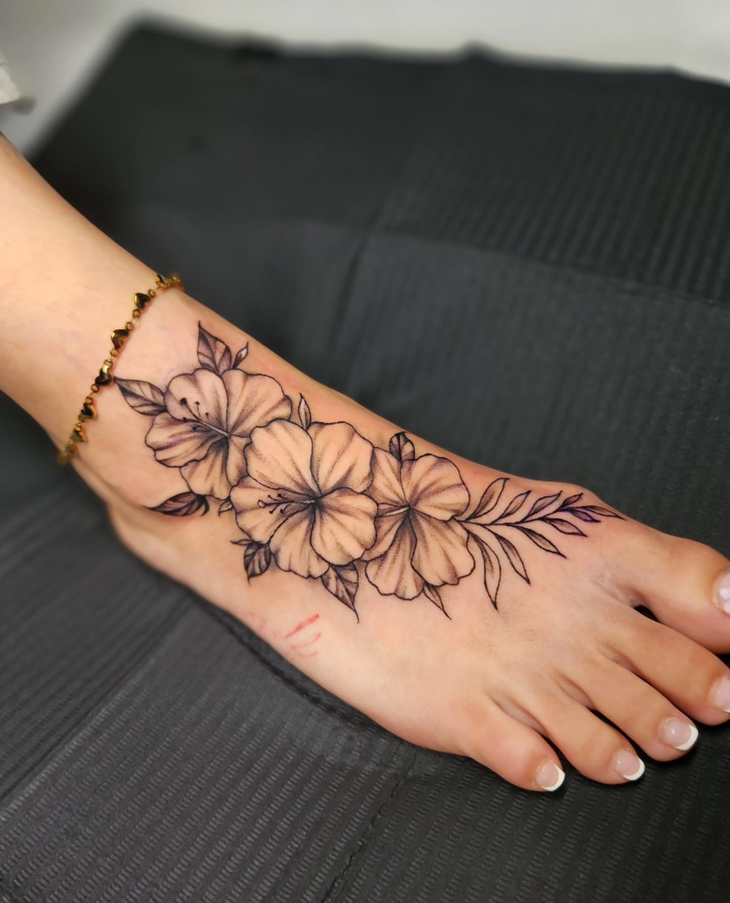 Hibiscus flowers black and grey tattoo on the foot by Abby Renteria