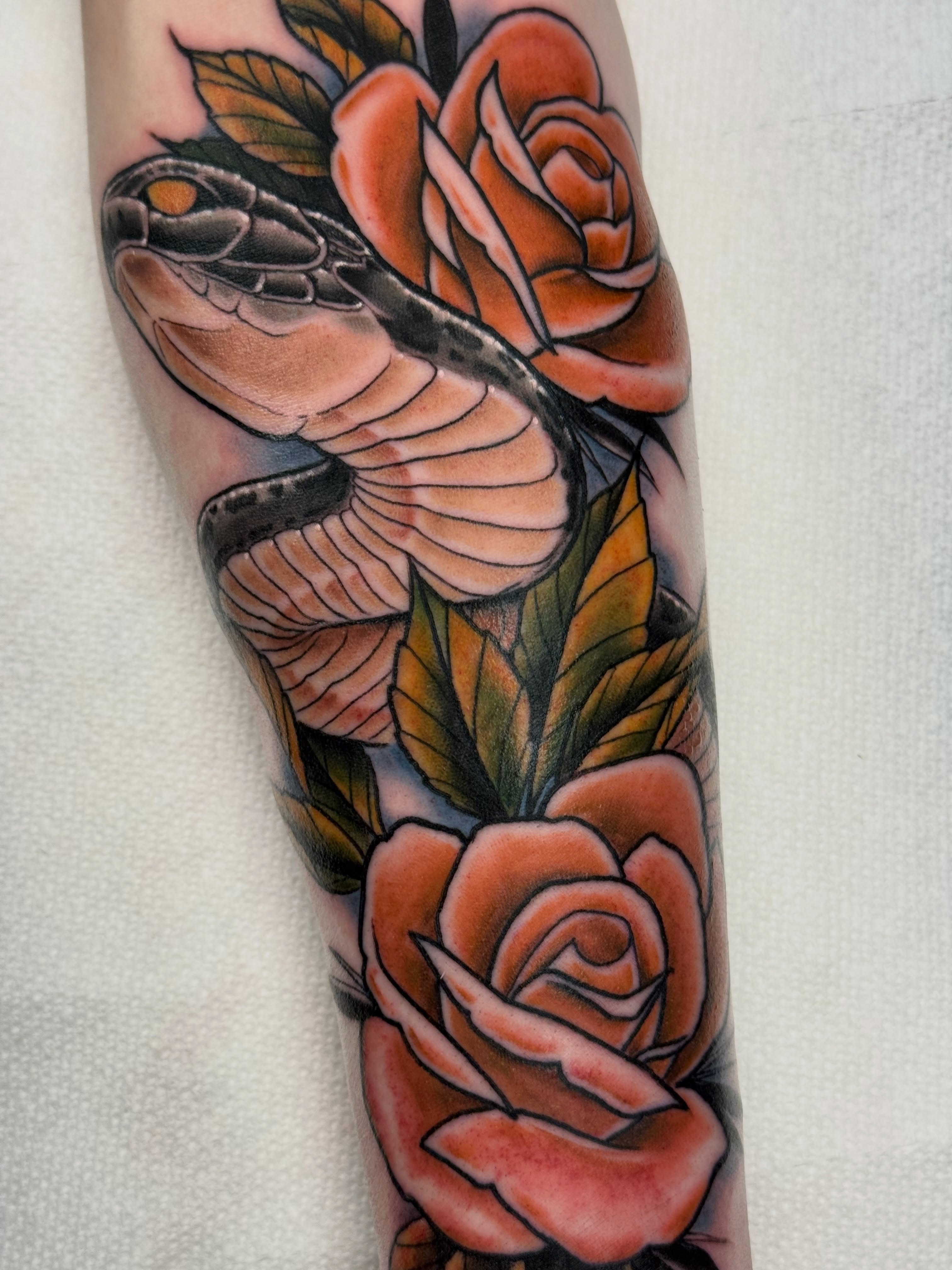 Snake and roses American traditional tattoo on the forearm by Justin Hay