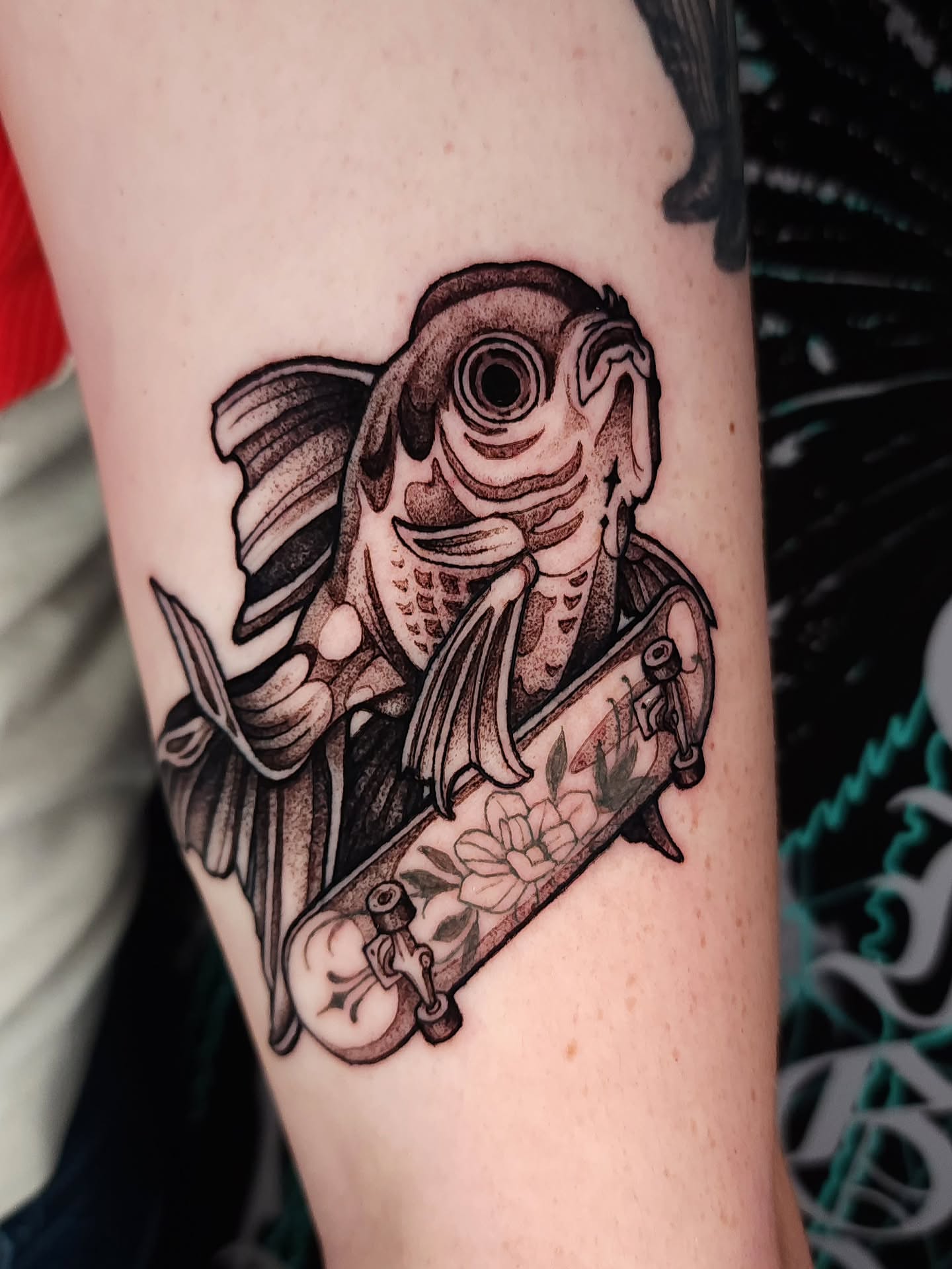 Fish and skateboard black and grey tattoo on the forearm by Mario Romero