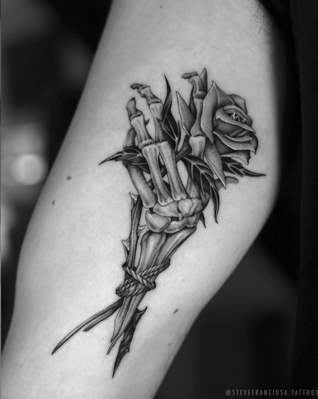 Skeleton hand holding a rose surrealism tattoo on the forearm by Steve Franciosa