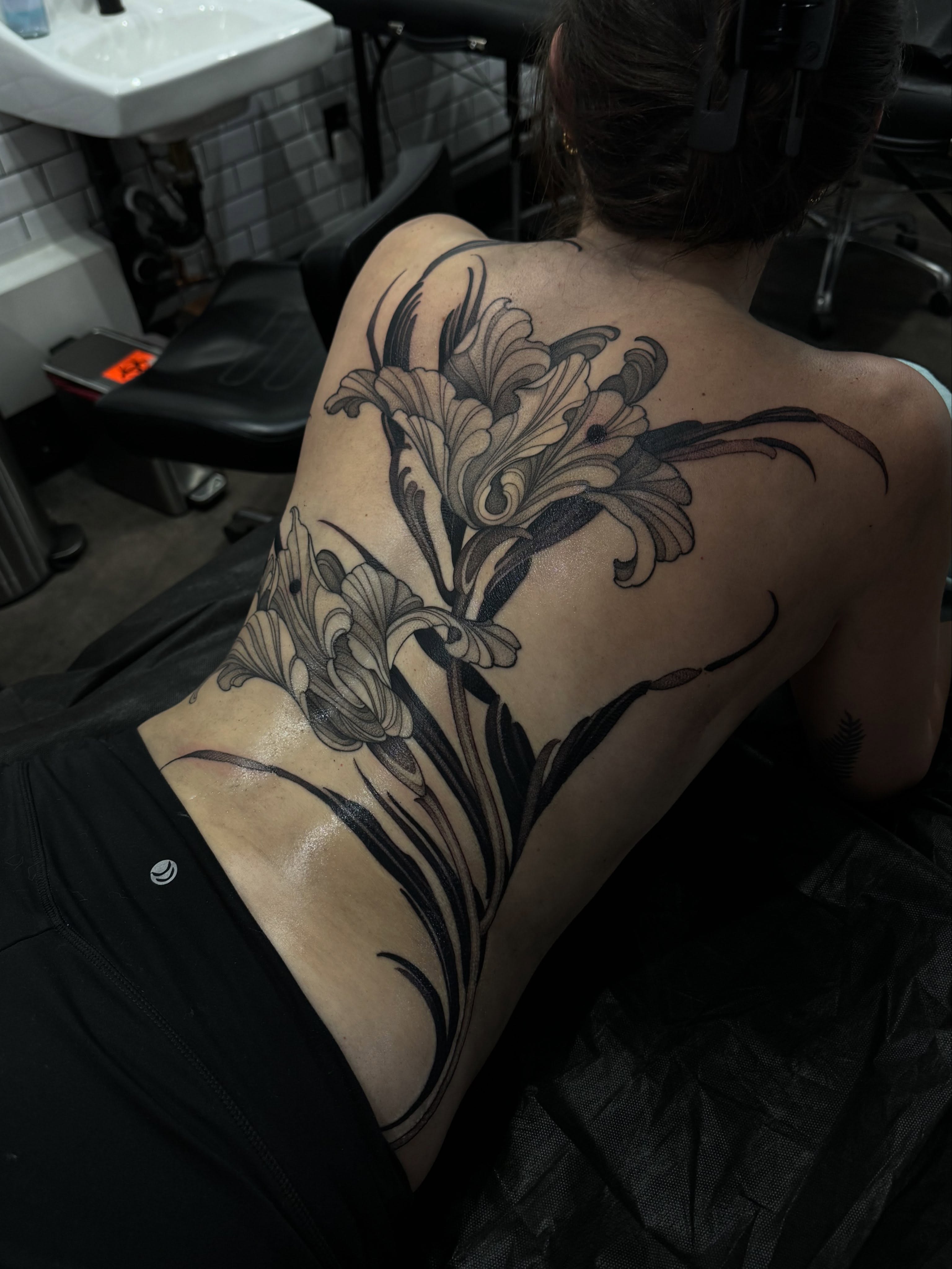 Lily black and grey tattoo on the back by Heather Apgar