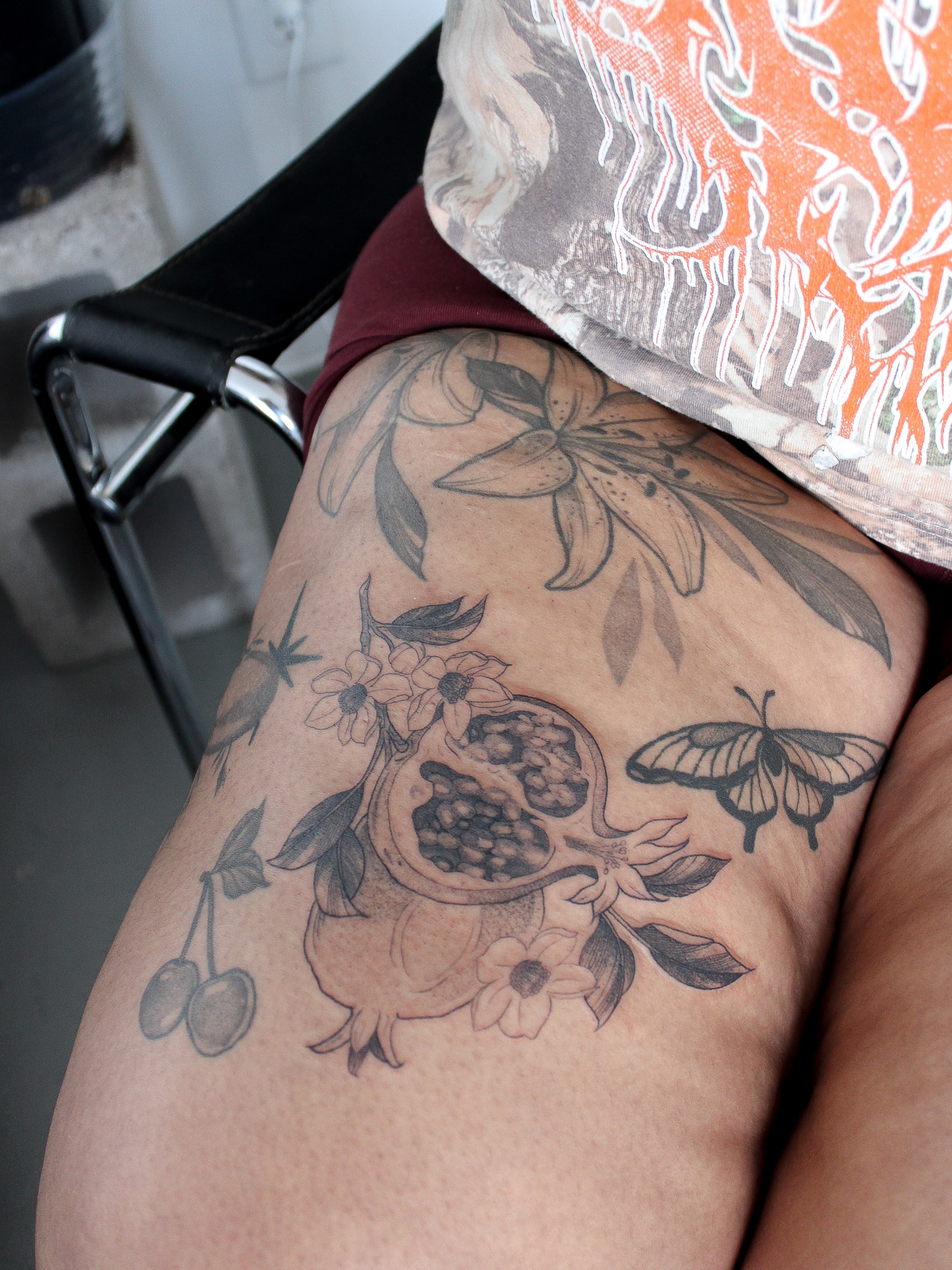 Fruit and floral arrangement realism tattoo on the thigh by Julianna