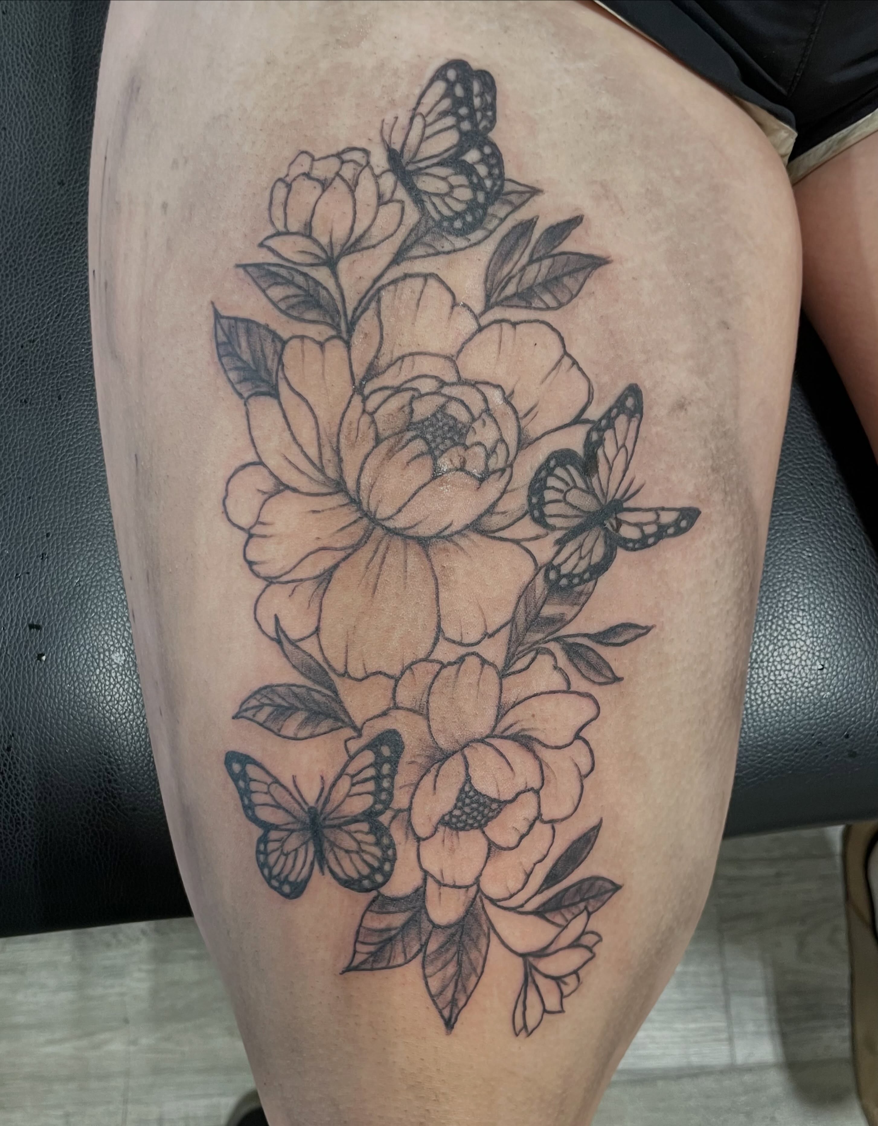 Peonies and butterflies black and grey tattoo on the thigh by Logan Casimir