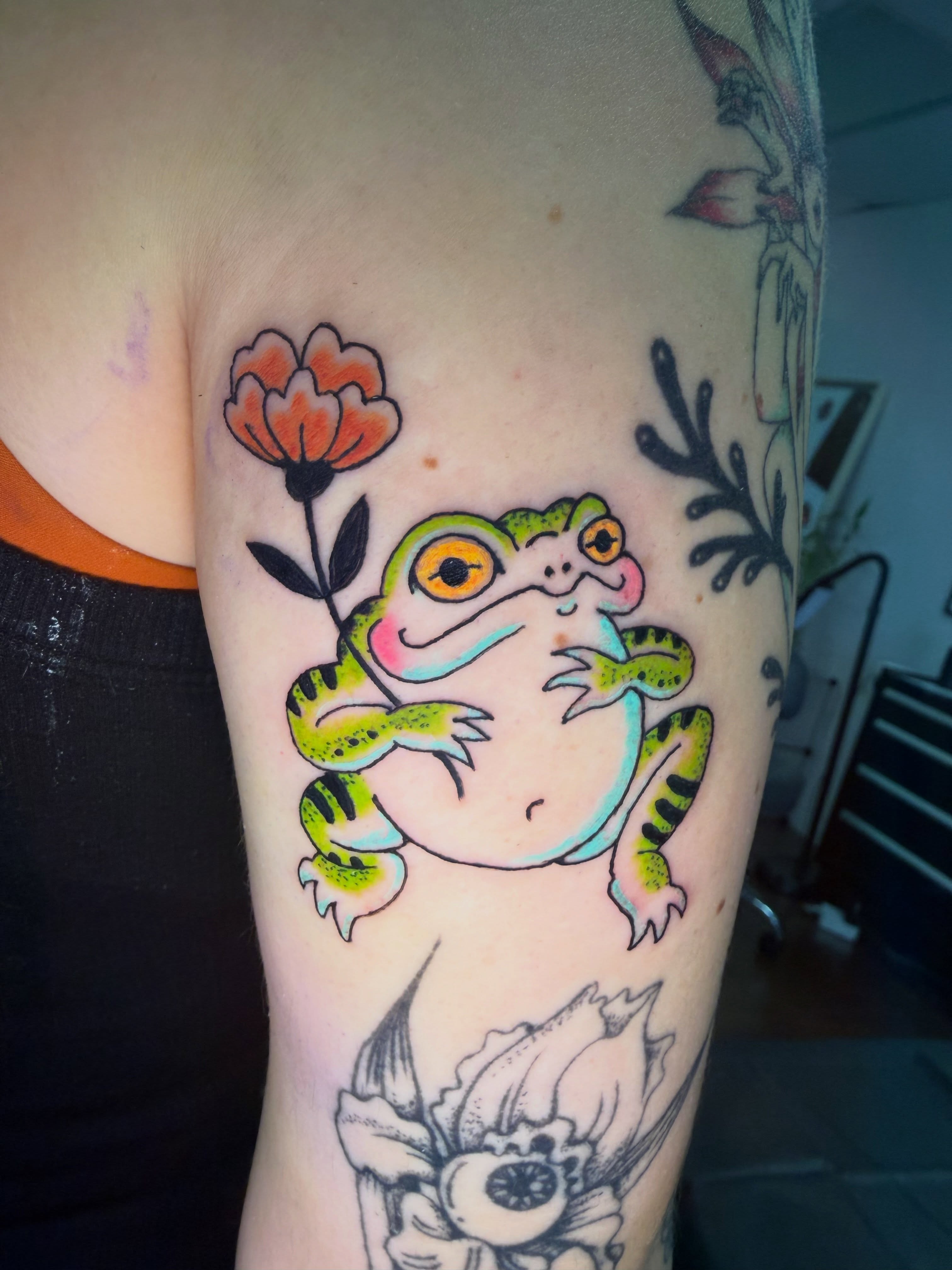 Frog holding flower new school tattoo on the forearm by Melissa Contreras