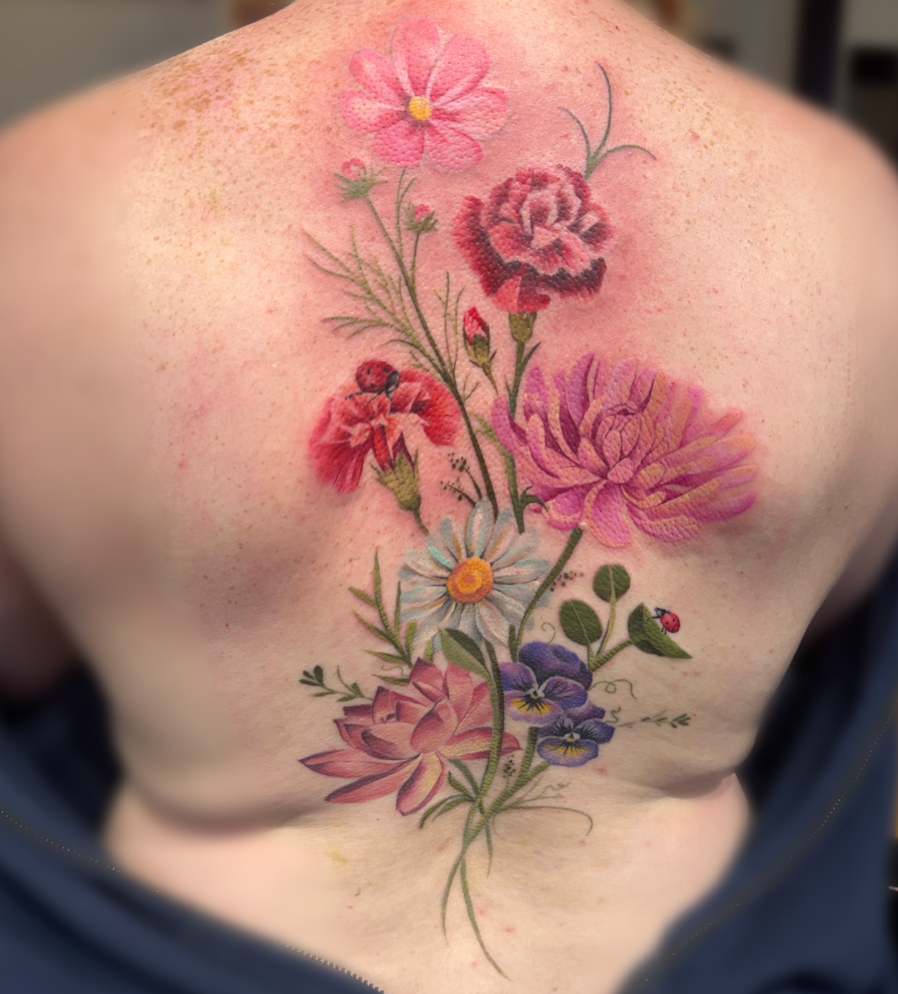 Floral bouquet realism tattoo on the back by Elly Bordwell