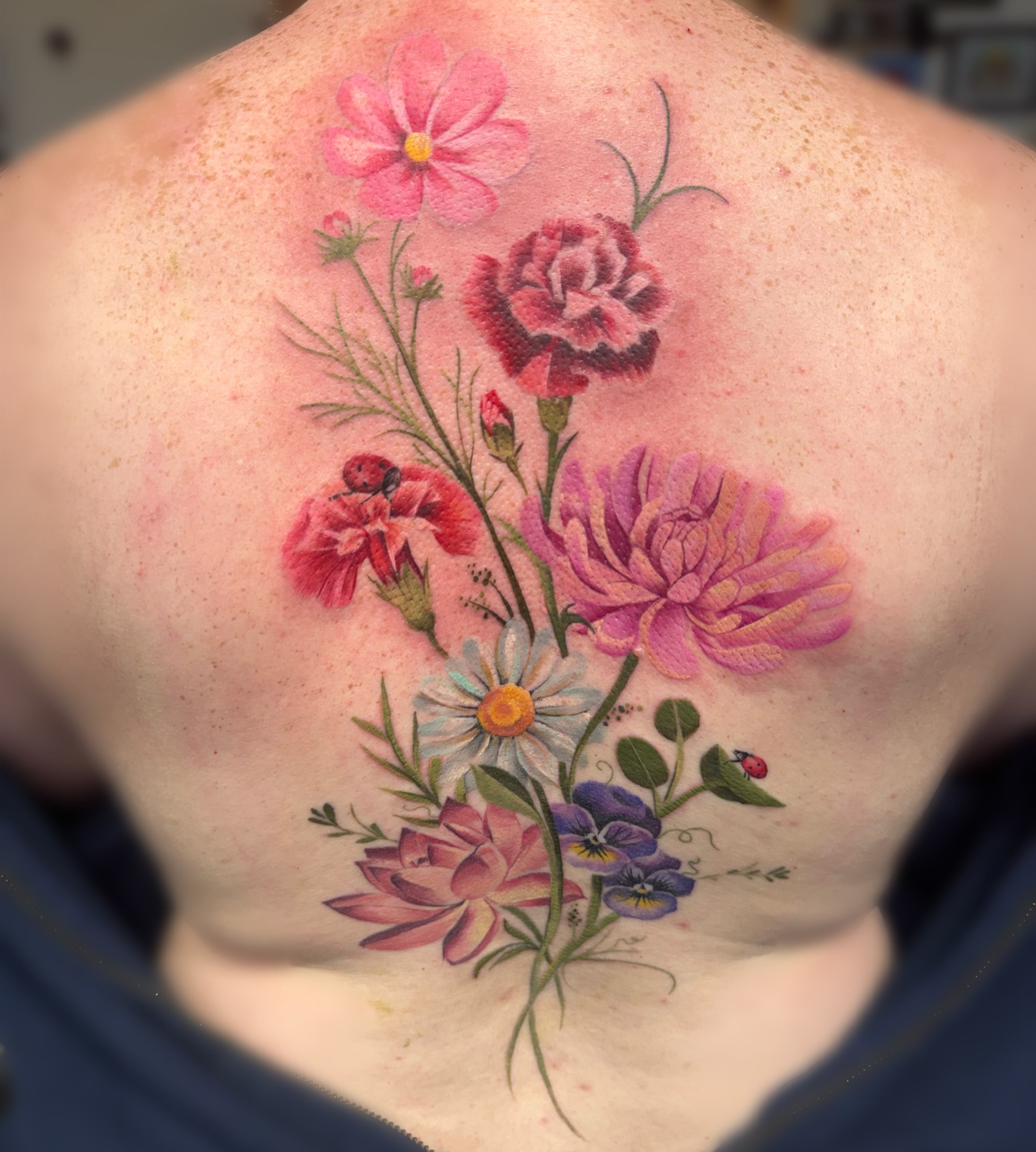 Floral bouquet realism tattoo on the back by Elly Bordwell