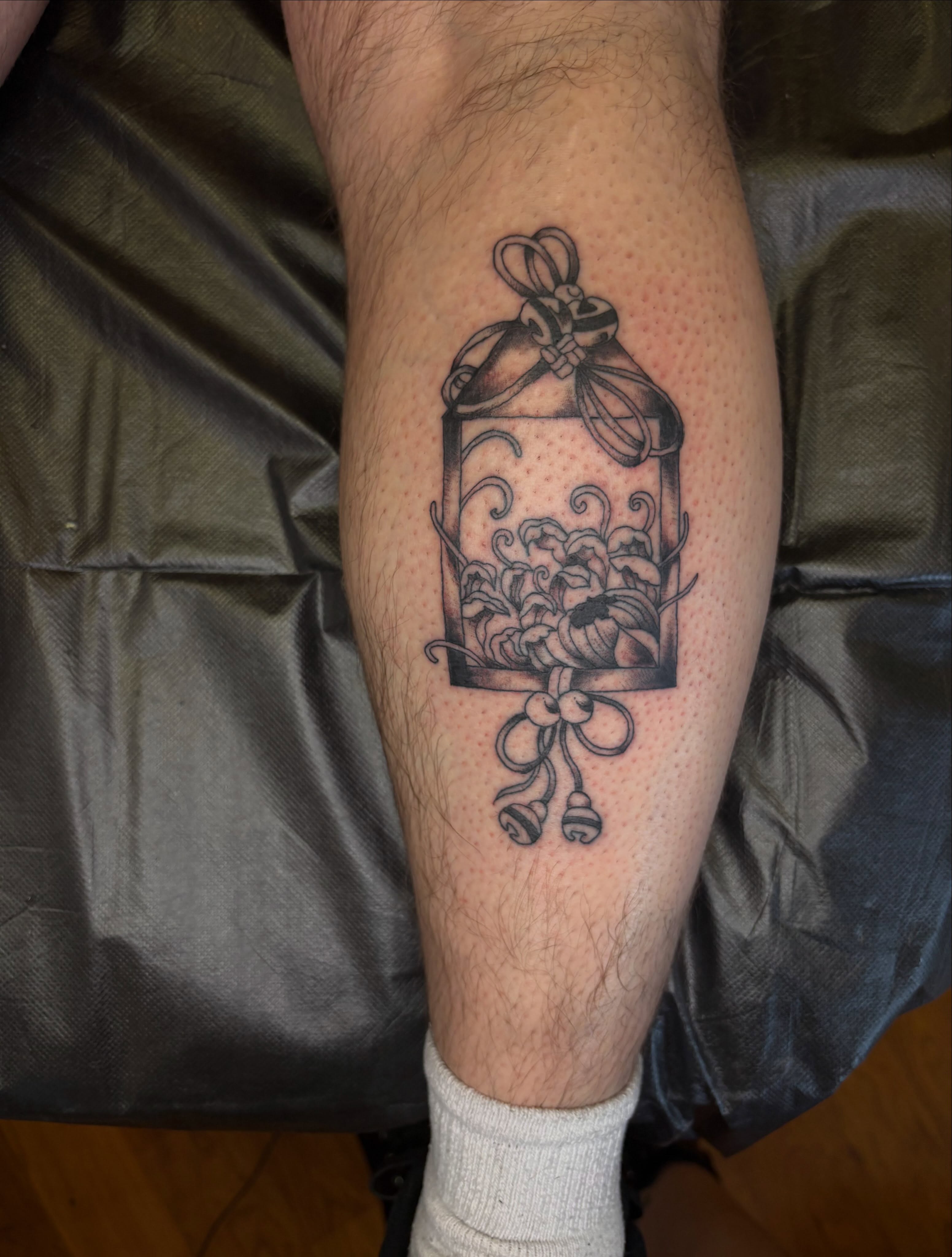 Birdcage with flowers black and grey tattoo on the forearm by Lauren Deets