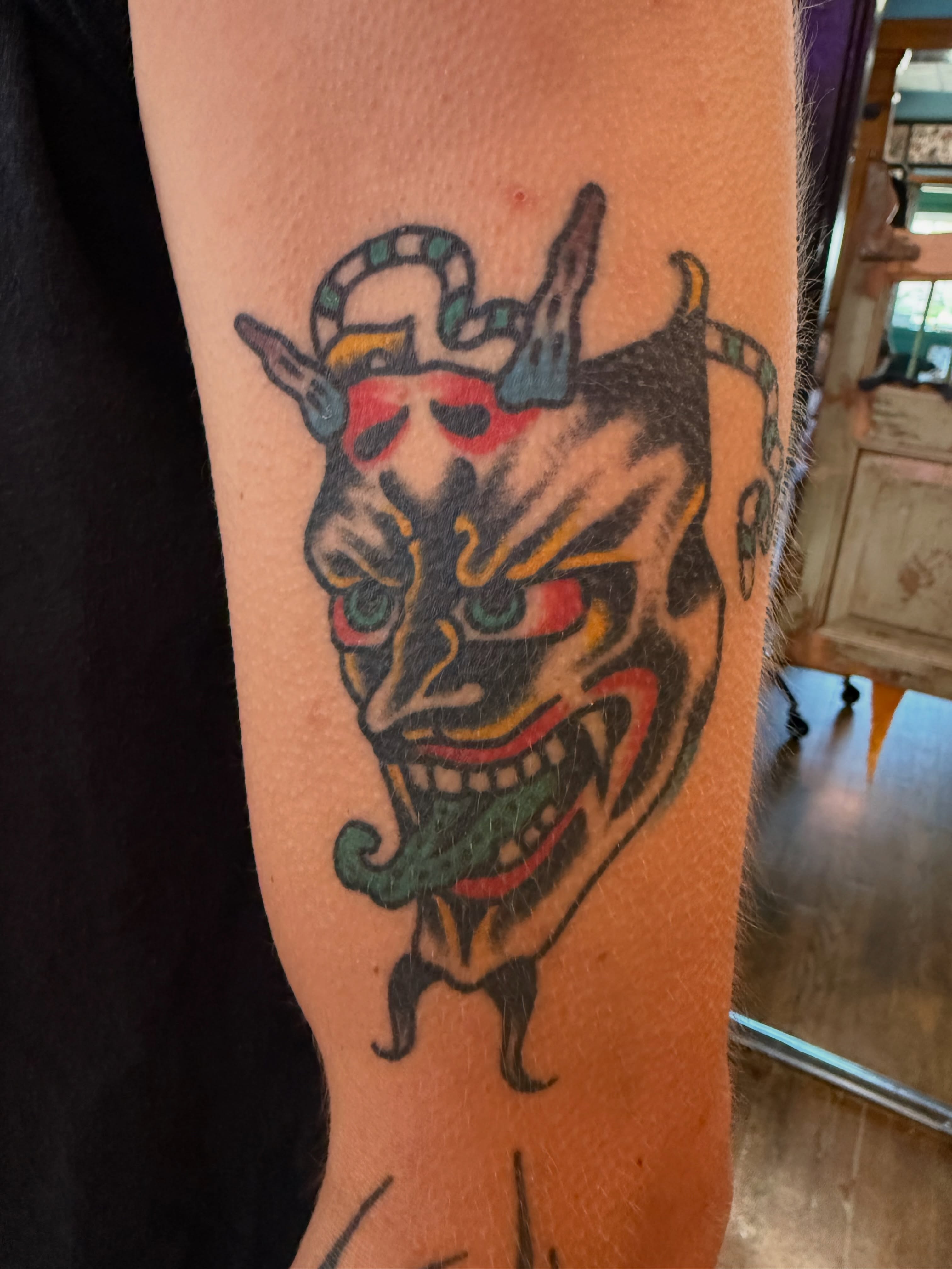 Demon mask American traditional tattoo on the forearm by Chuck Derek Whitaker