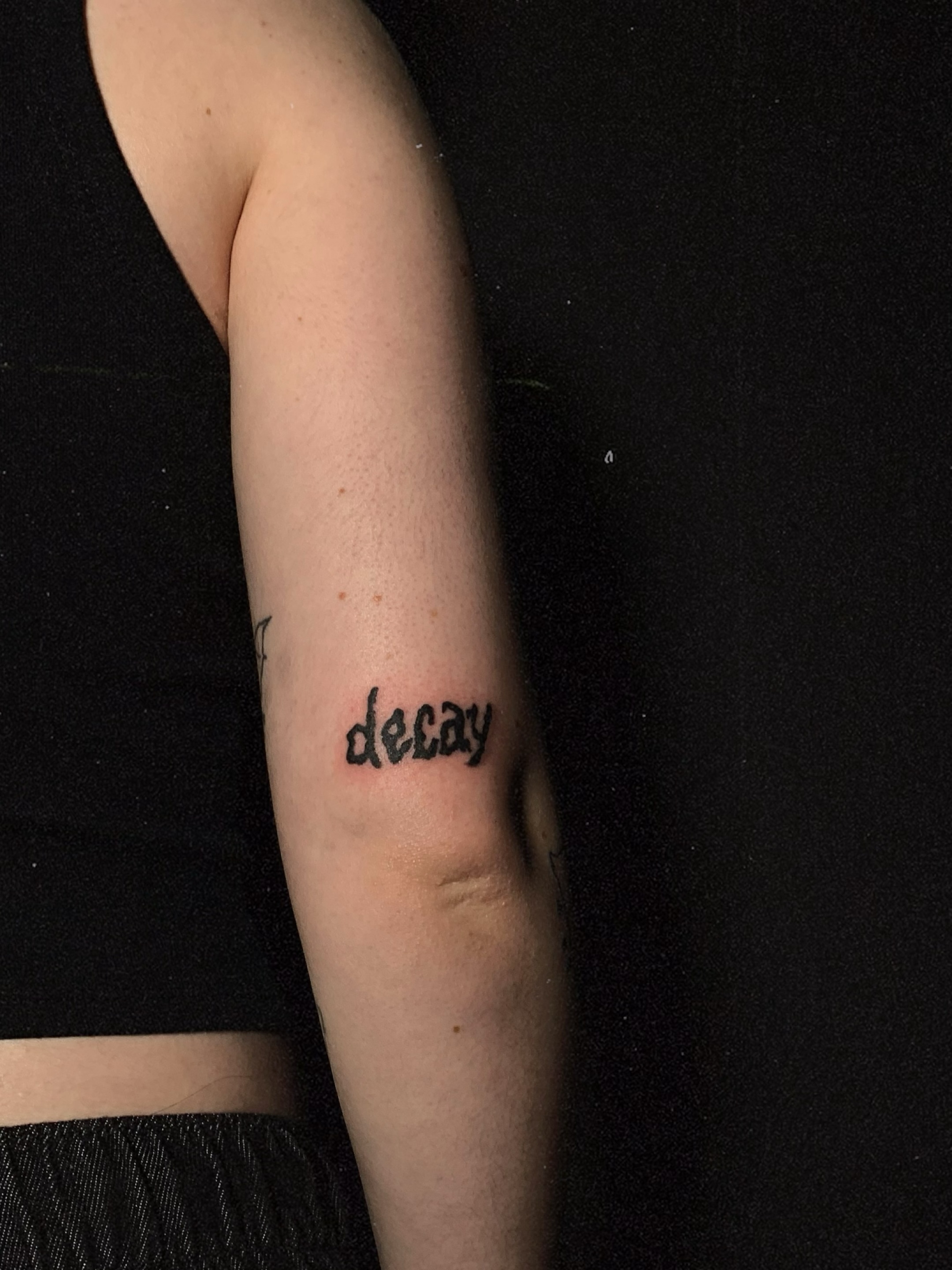 Decay lettering script tattoo on the forearm by charles