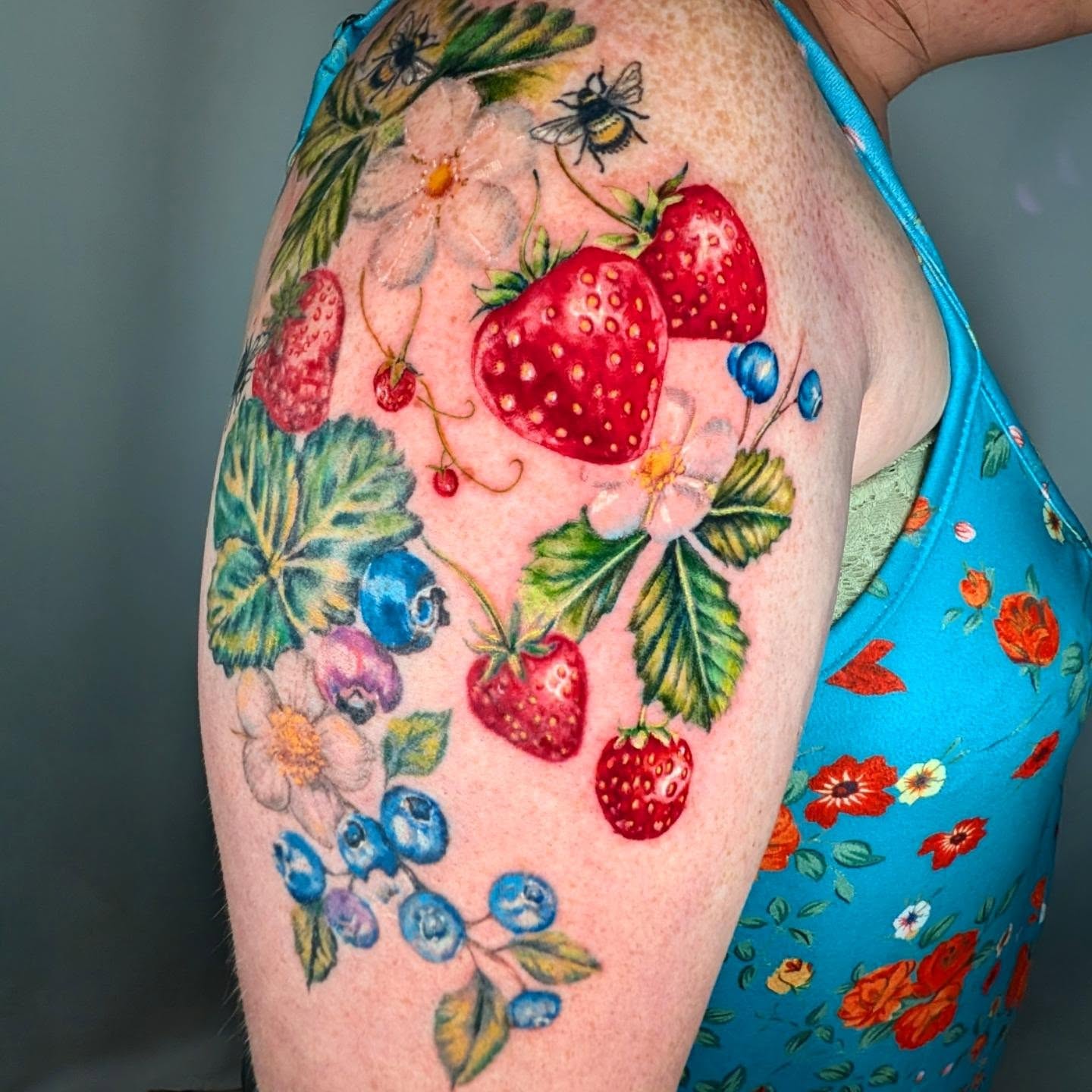 Berries and flowers watercolor tattoo on the shoulder by Madelynne