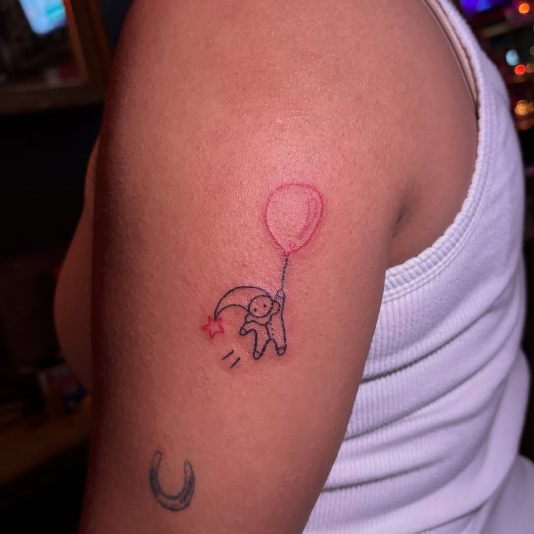 Balloon and astronaut minimalist tattoo on the upper arm by ☠️mikauley☠️